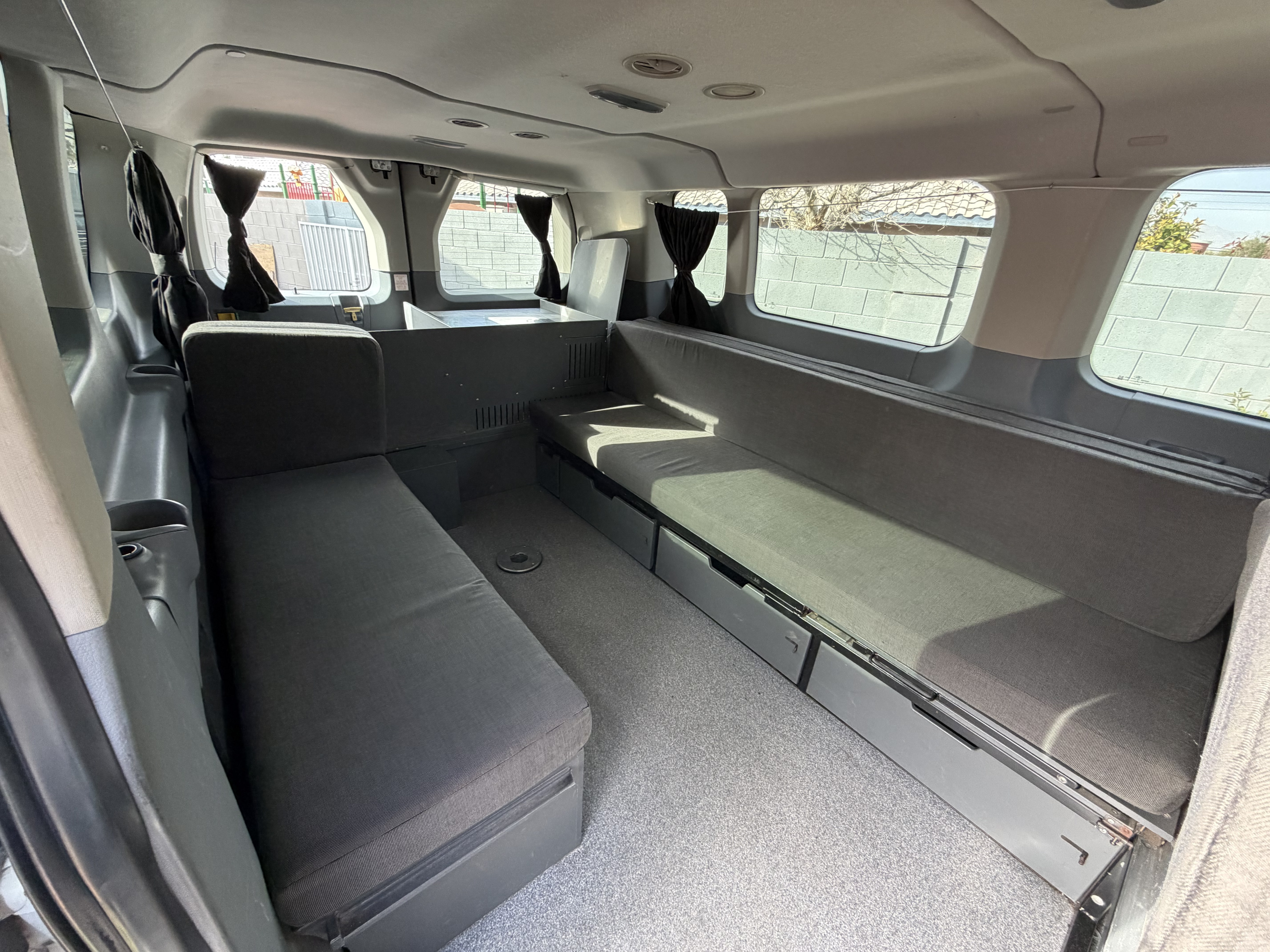 RV rental's custom camper van interior: comfortable bench seating, convertible sleeping area, and practical under-seat storage.. Ford Transit 2017