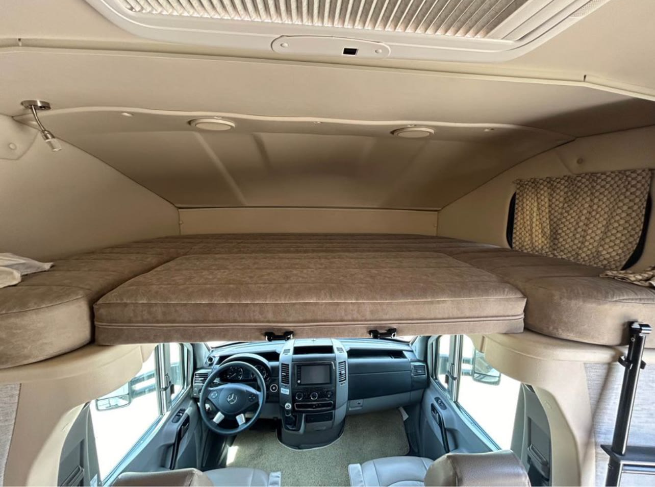 Inside an rv rental: a comfy cab-over bunk bed overlooks the spacious driver's cockpit area.. Winnebago View 2018