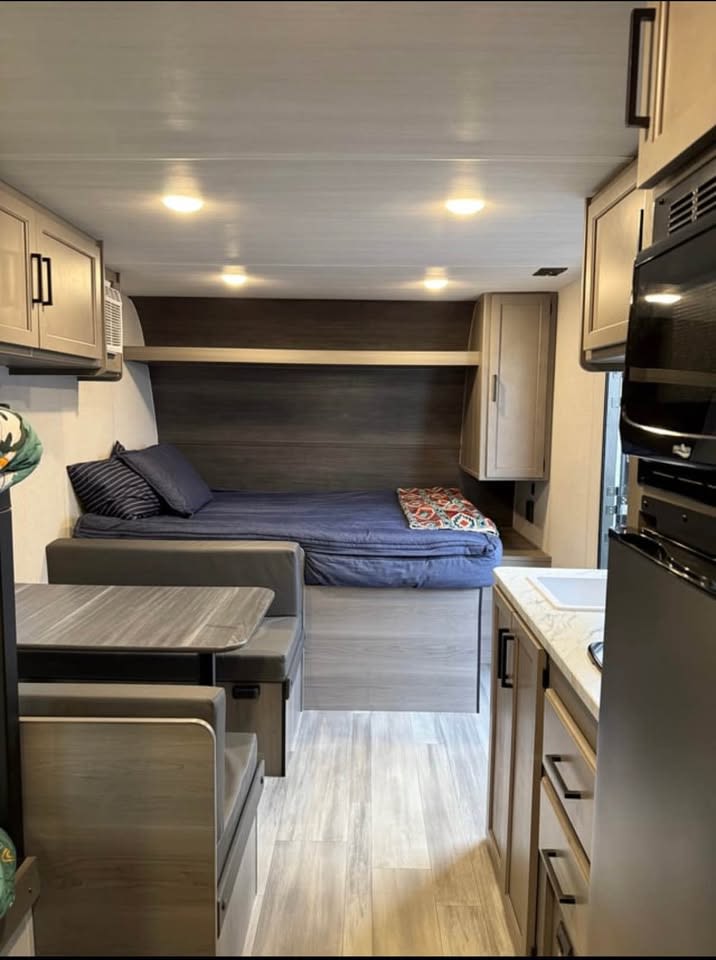 RV rental interior with a cozy bed, dinette, and compact kitchen space, perfect for road trip adventures.. Keystone RV Hideout Sport 2024