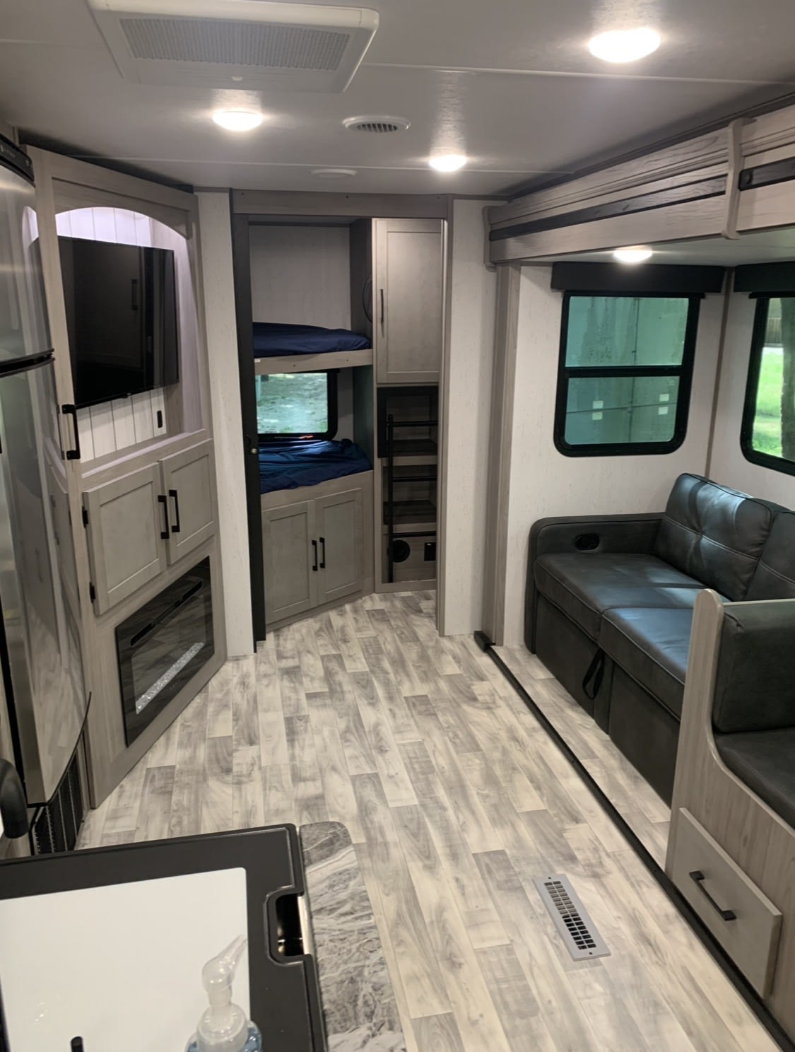 Modern RV rental interior with living area, kitchen counter, TV, bunk beds, and light wood-look flooring.. Dutchmen Kodiak Ultra Lite 2022