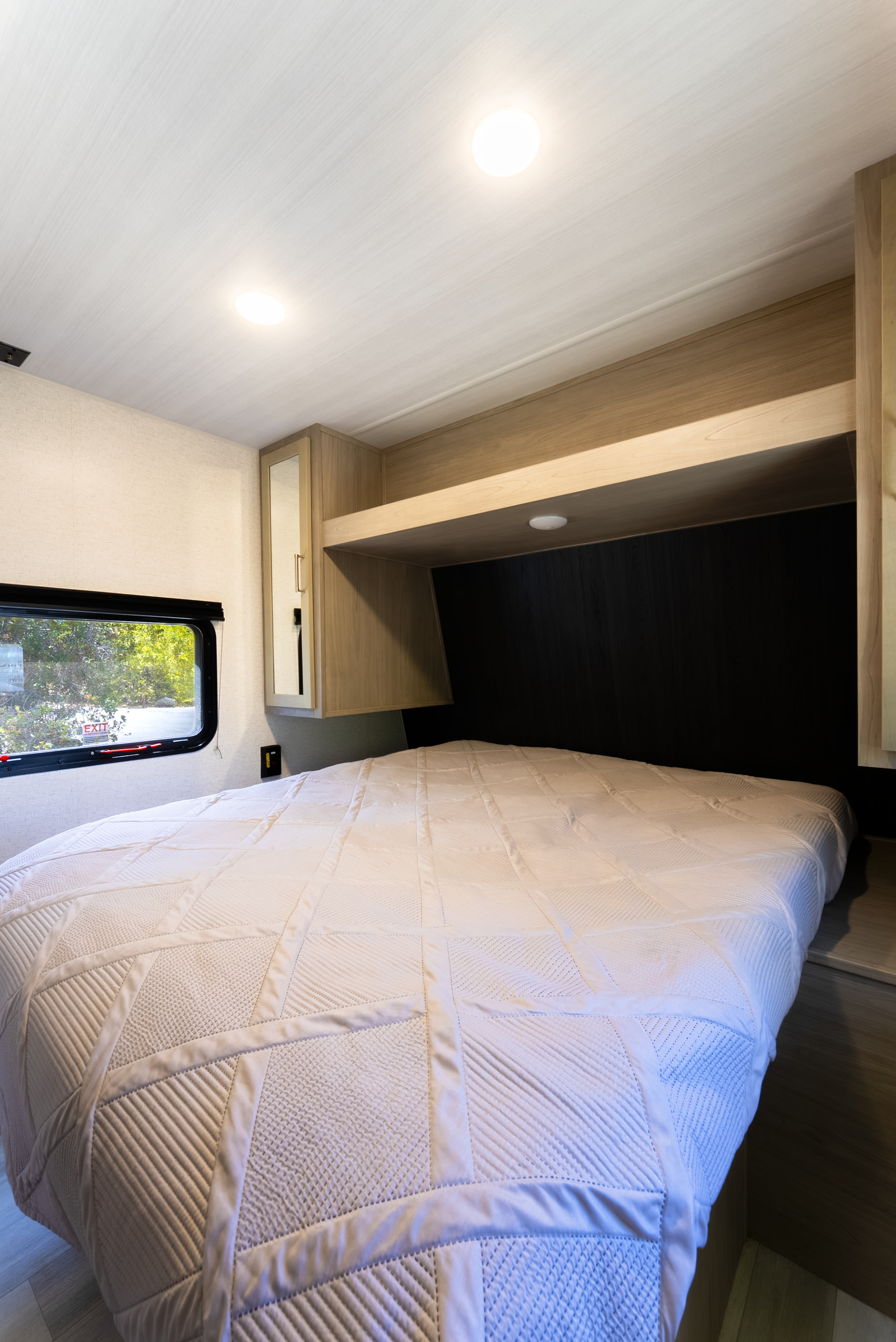 Modern RV rental bedroom interior with a comfy bed, overhead storage, and large window. Perfect for your next trip.. Keystone Springdale 2024