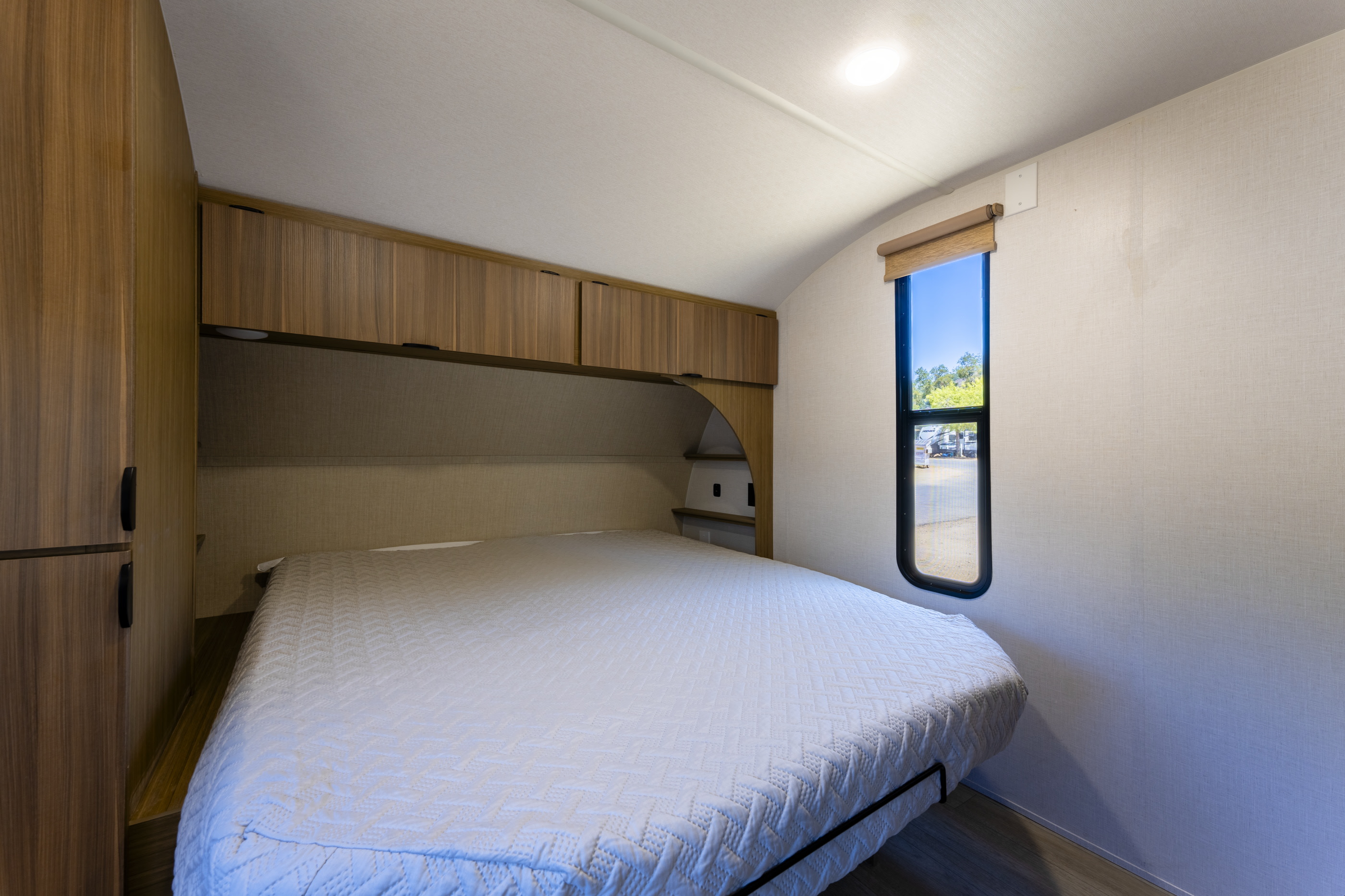 Inside a comfortable RV rental bedroom featuring a bed, ample storage, and a window for natural light.. Wildwood X-Lite 25ICE 2025