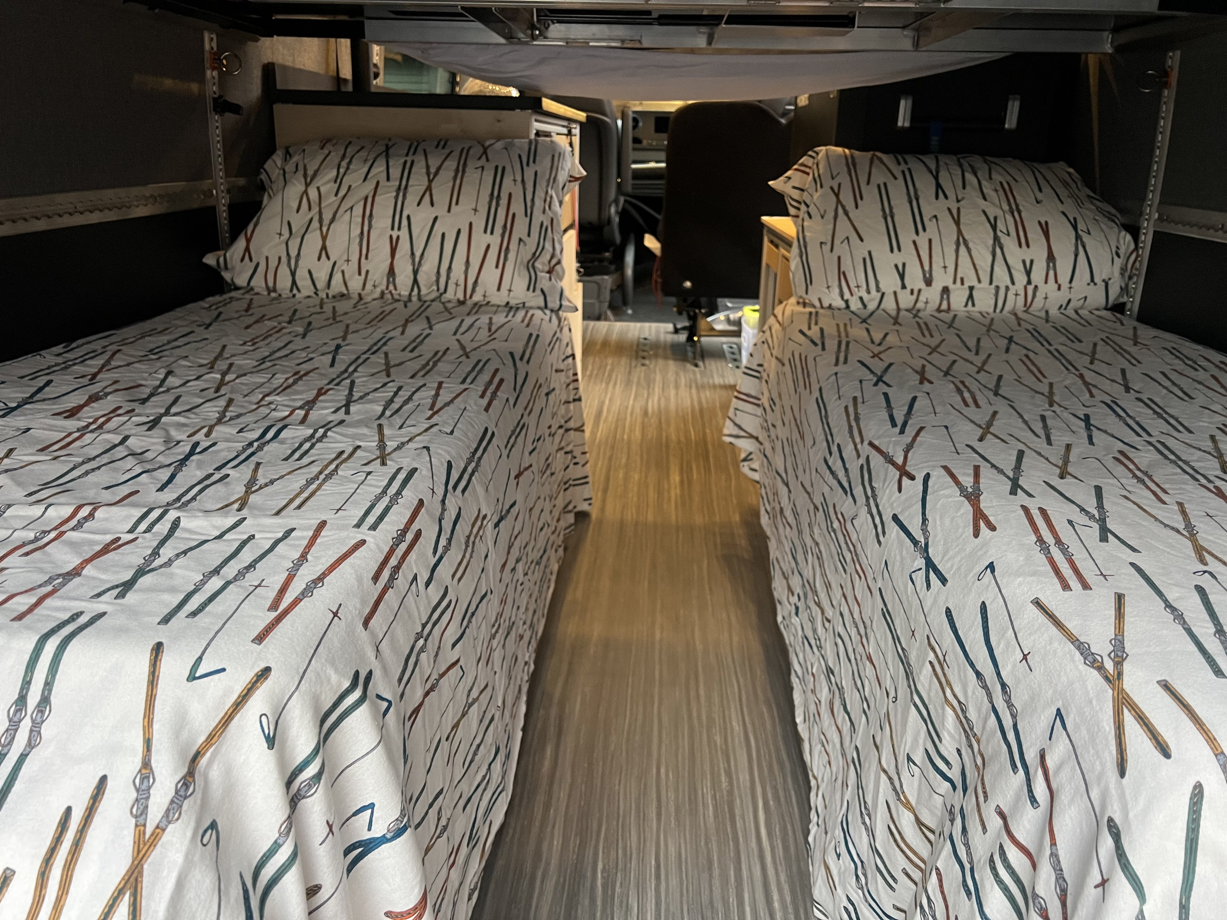 Cozy RV rental interior with two narrow beds featuring ski-themed bedding, ready for adventure.. Mercedes Sprinter 2022