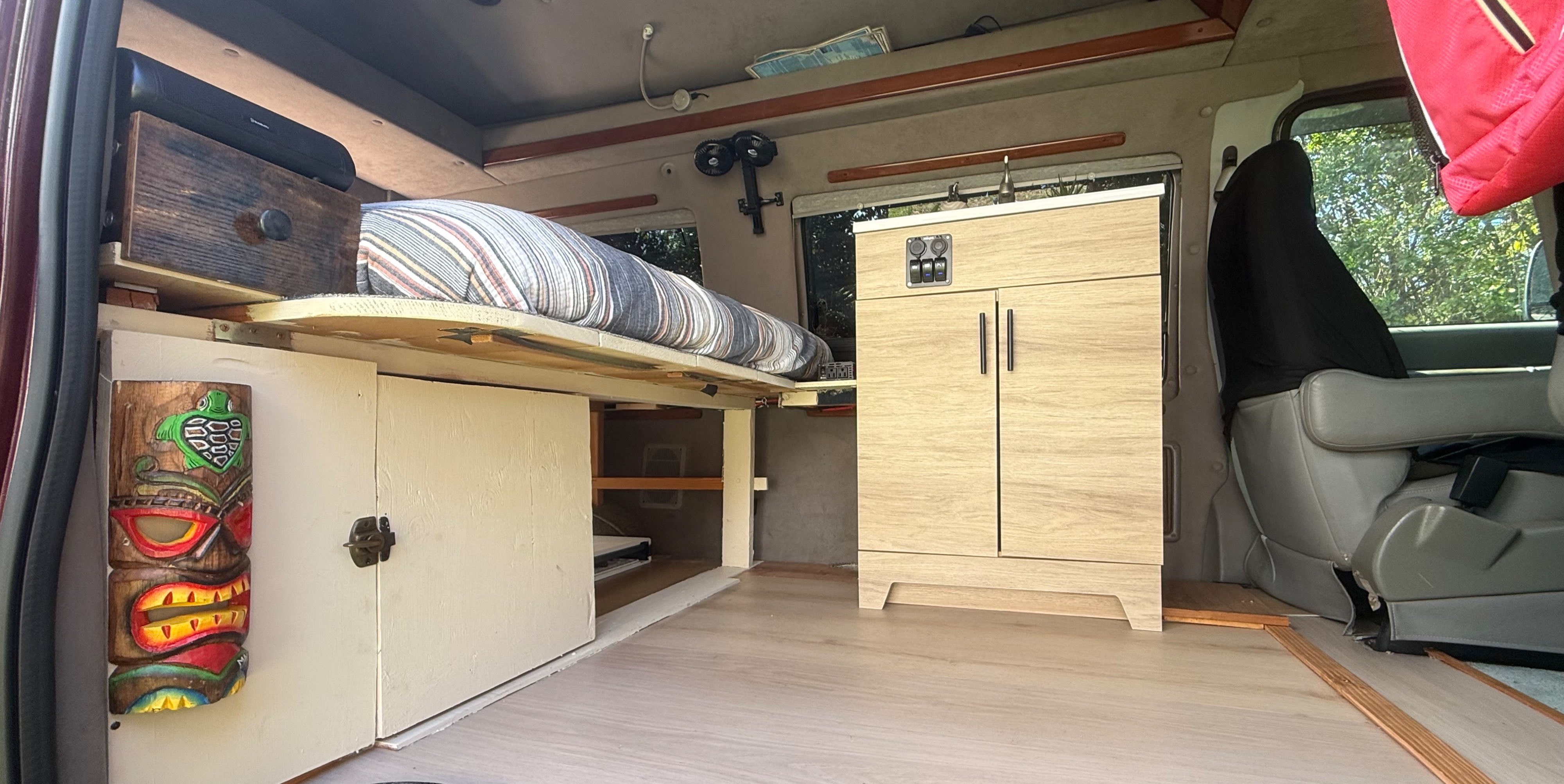 Inside this custom rv rental: raised bed, storage cabinets, and power controls for a functional adventure.. Ford Econoline Club Wagon 2005