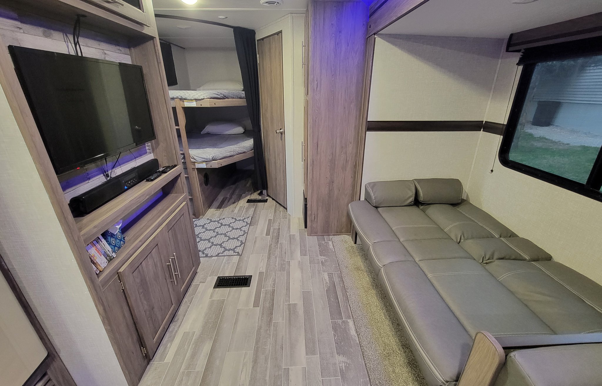Modern rv rental interior featuring a TV, cozy bunk beds, and a versatile convertible sofa.. Crossroads RV Zinger Lite 2022