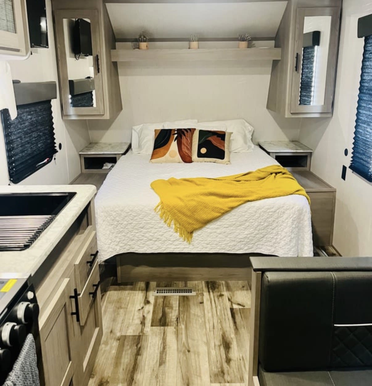 Experience a modern RV rental! Features a cozy bedroom with queen bed, yellow throw, built-in storage, and a sleek kitchen.. Dutchmen Coleman Lantern LT 2022