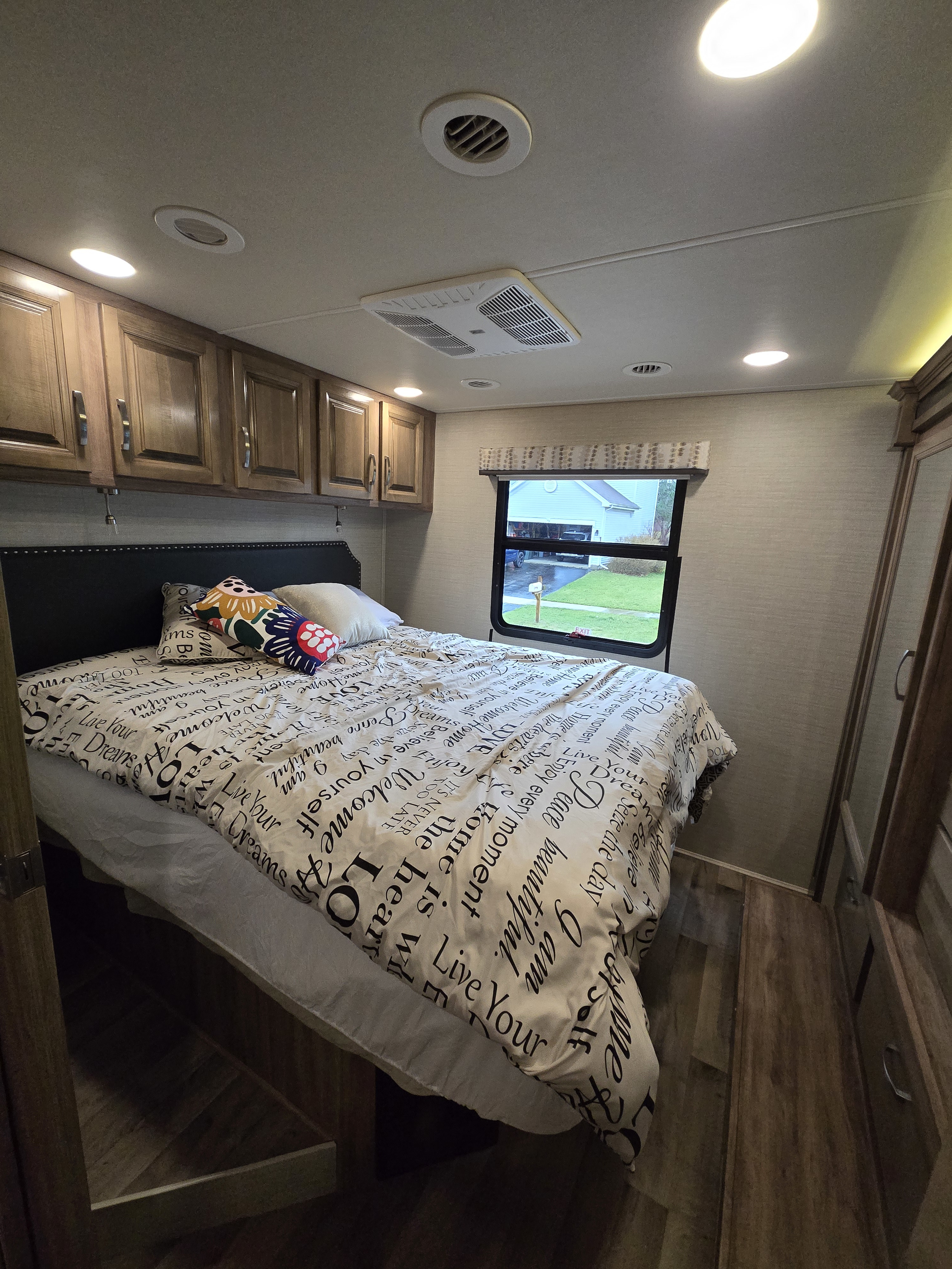 Cozy RV bedroom with a bed, overhead storage, AC, and a view outside, perfect for your rv rental adventure.. Jayco Precept 2019