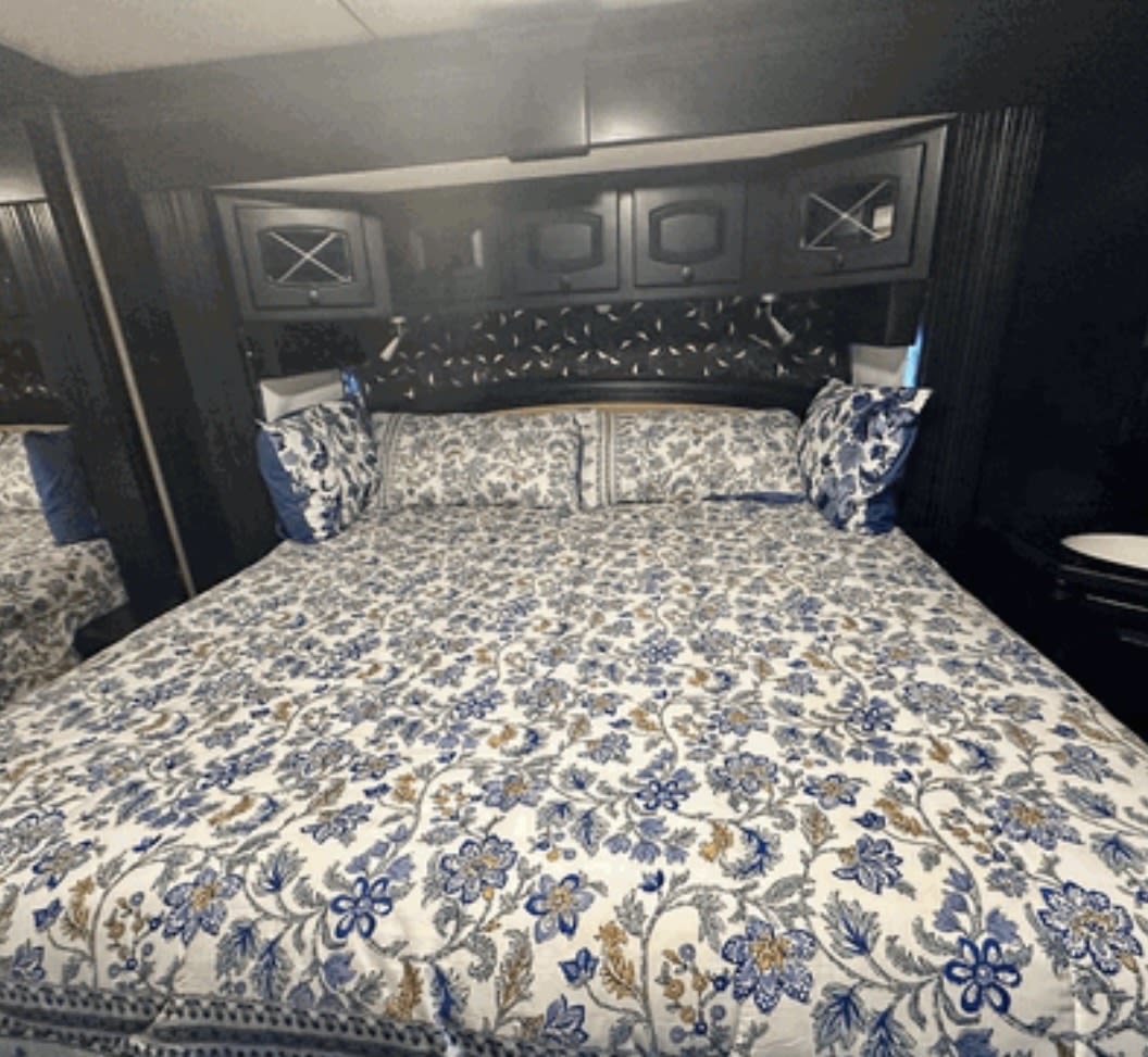 RV rental bedroom: cozy bed with blue floral bedding & dark wood cabinets. Perfect for your next trip!. Newmar Dutch Star 2008