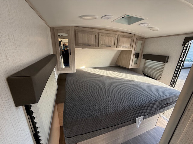 This inviting RV rental bedroom features a large bed, overhead cabinets, and windows with blinds, perfect for a comfortable adventure.. Cruiser RV Shadow Cruiser 248RKS 2022