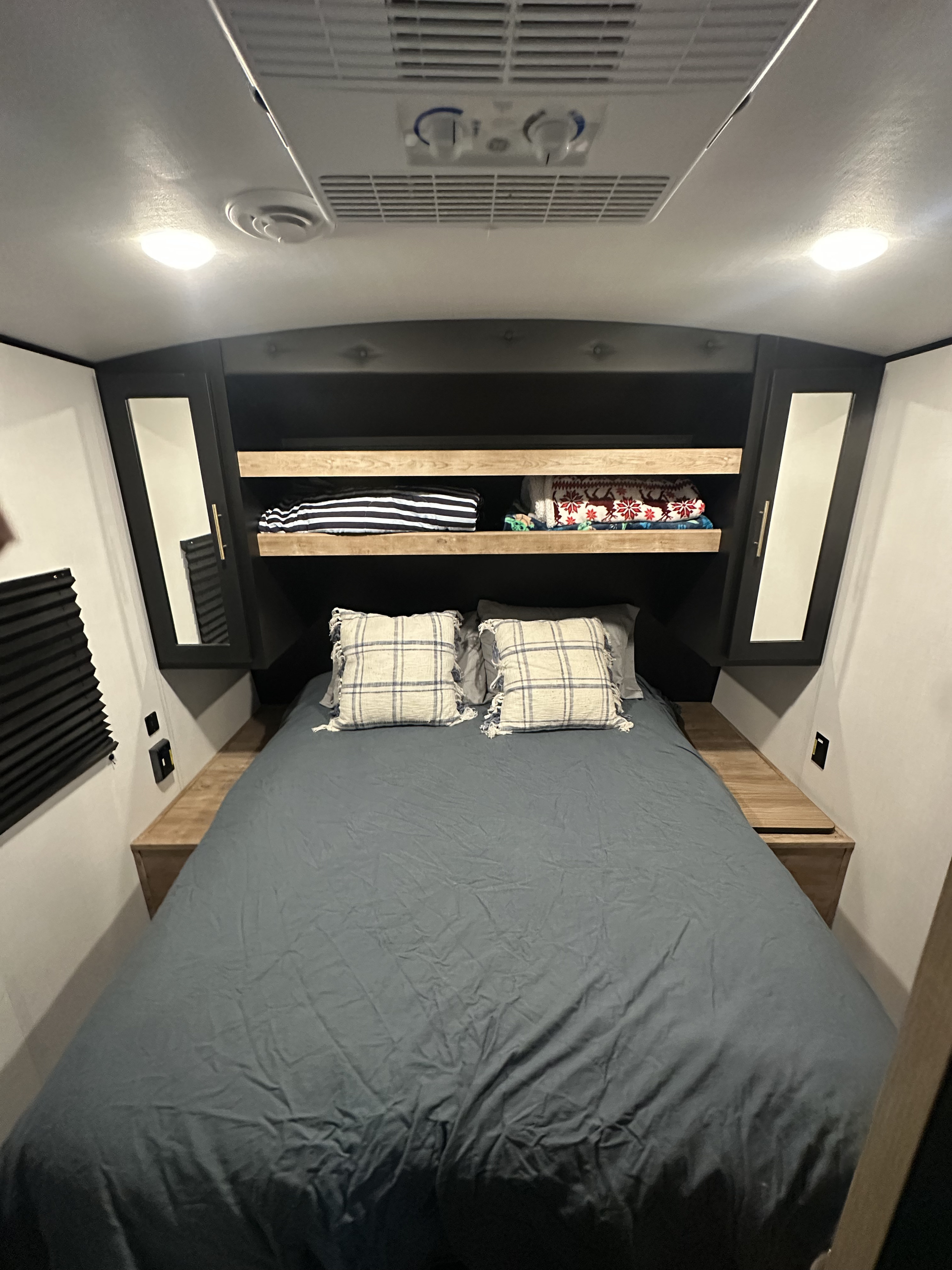 Cozy RV rental bedroom with a comfy bed, overhead storage, side cabinets, and a ceiling AC unit.. Keystone RV Springdale 2023