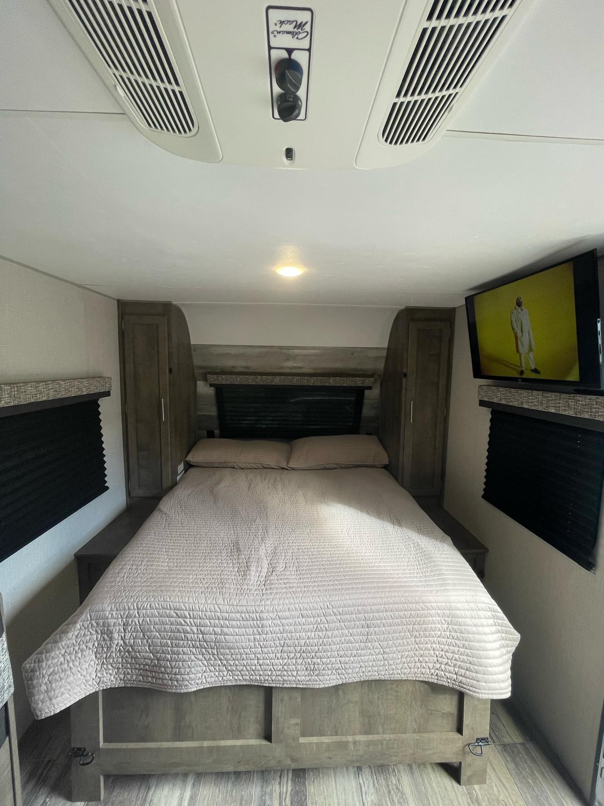 Cozy RV rental bedroom featuring a queen bed, TV, AC, and built-in storage. Ideal for your next road trip adventure.. KZ Escape 2020