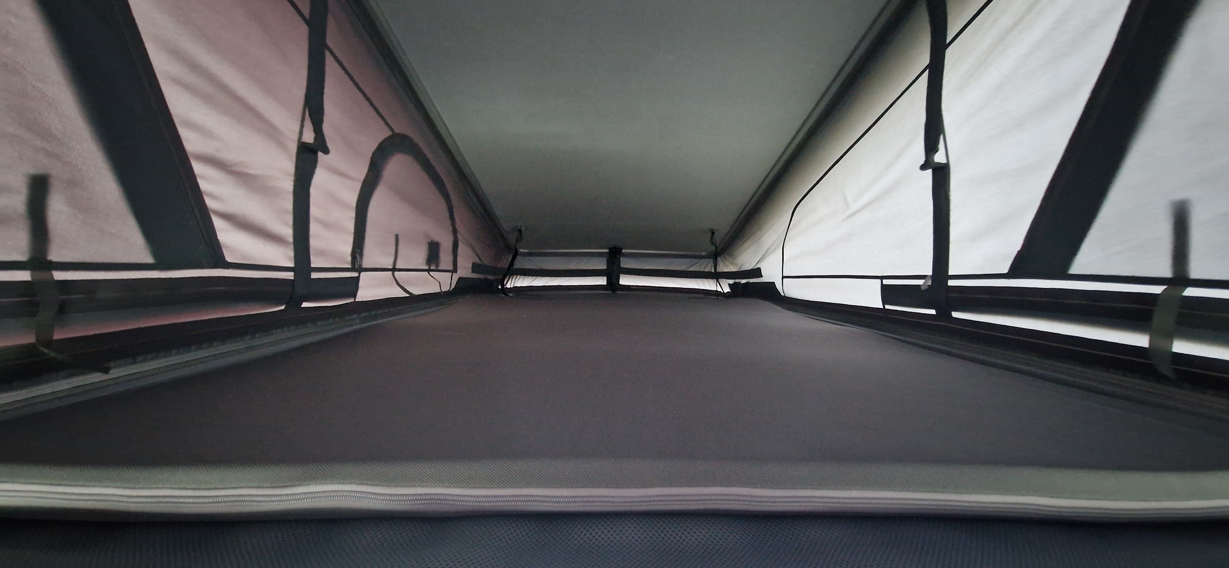 Elevated sleeping area inside an rv rental pop-up roof tent, showing fabric walls and ceiling.. Ford Transit Custom 2024