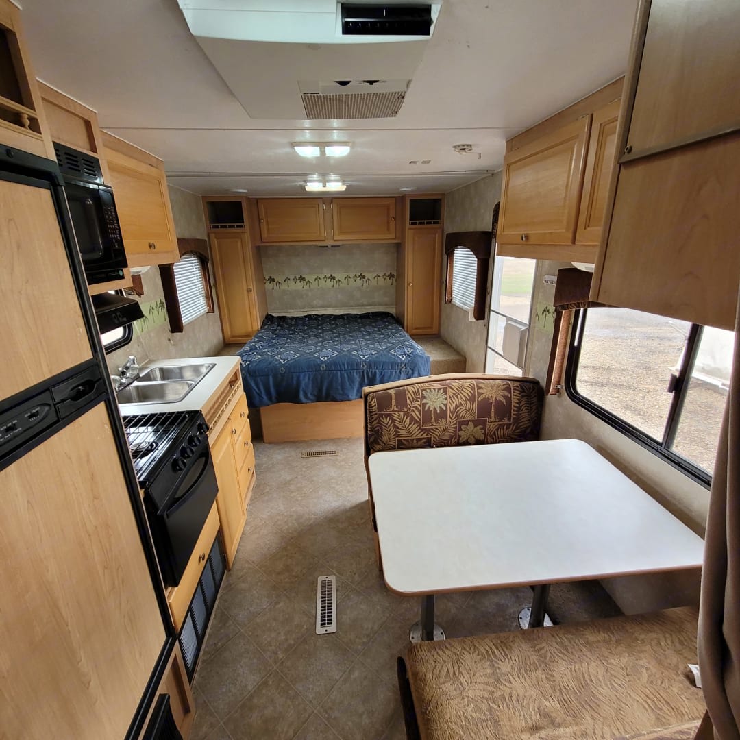 Spacious RV rental interior featuring a full kitchen, comfortable bed, and dinette seating for your next adventure.. Thor Wave 2006