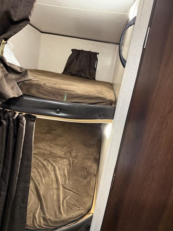 Compact bunk beds in an rv rental, featuring brown blankets and curtains, provide cozy sleeping space.. Jayco Jay Flight SLX Baja Edition 2019