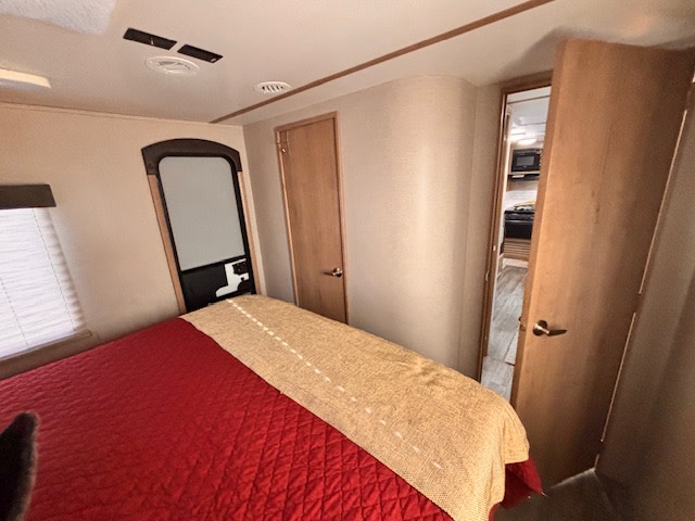 Cozy RV rental bedroom with comfy bed, window, and partial view of kitchen. Perfect for your camper adventure.. Winnebago 2401RG 2020