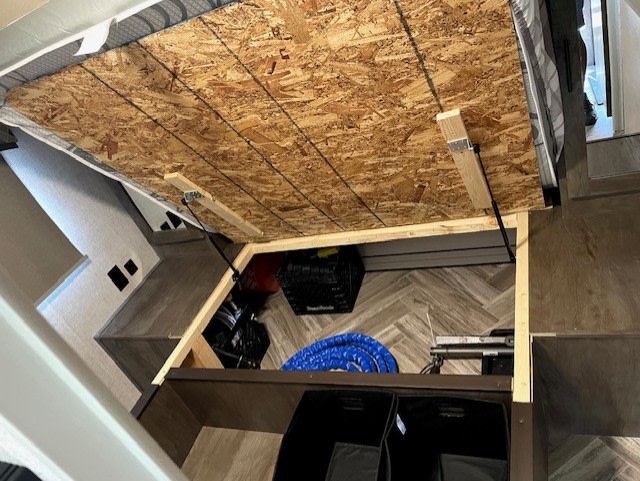 RV rental: Under-bed storage area in an RV, with the bed base lifted by gas struts, ideal for gear.. Forest River Evo 2021