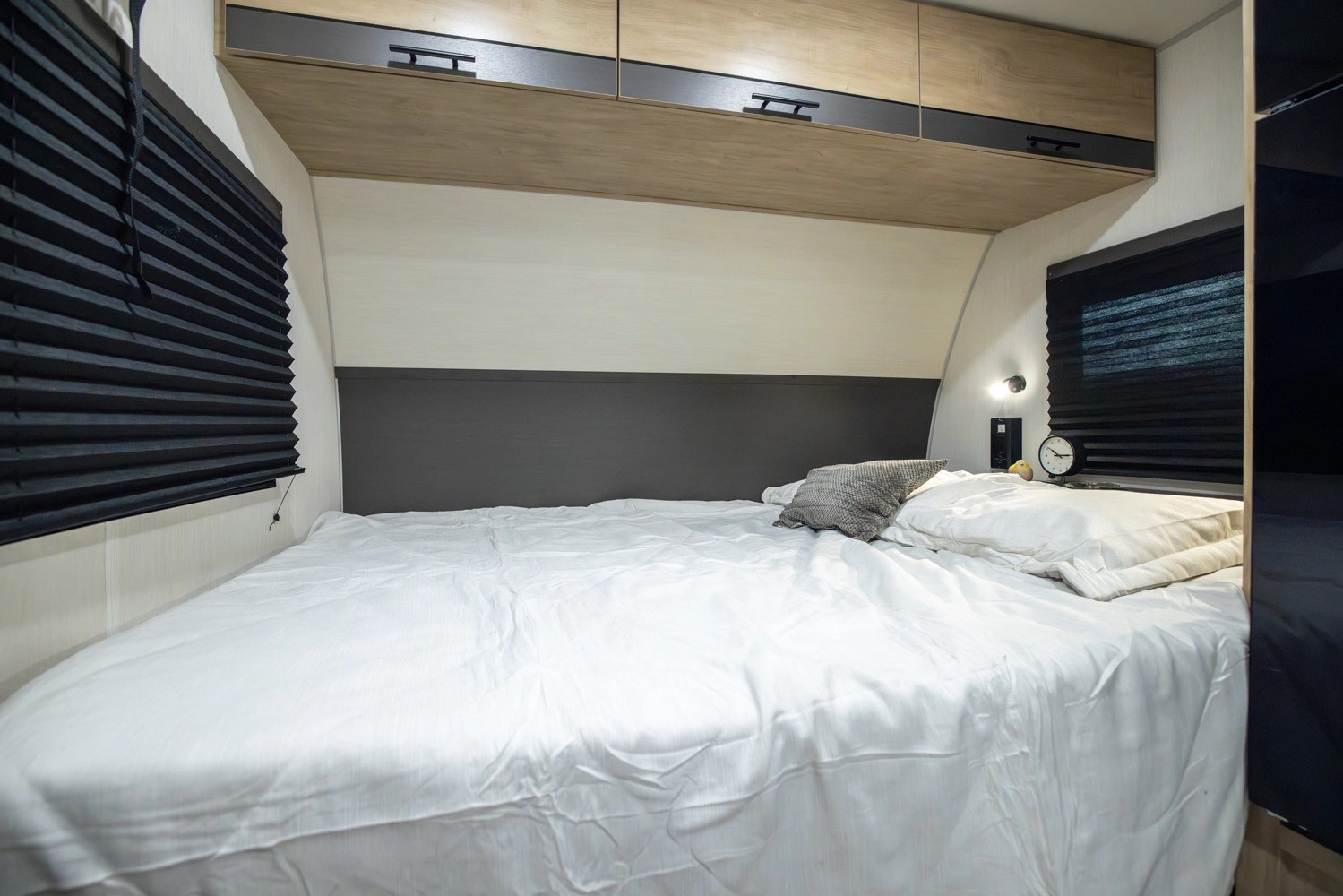 Cozy RV rental bedroom featuring a comfortable white bed, overhead storage, and windows with black pleated blinds.. Forest River Campsite Reserve 17LS 2026
