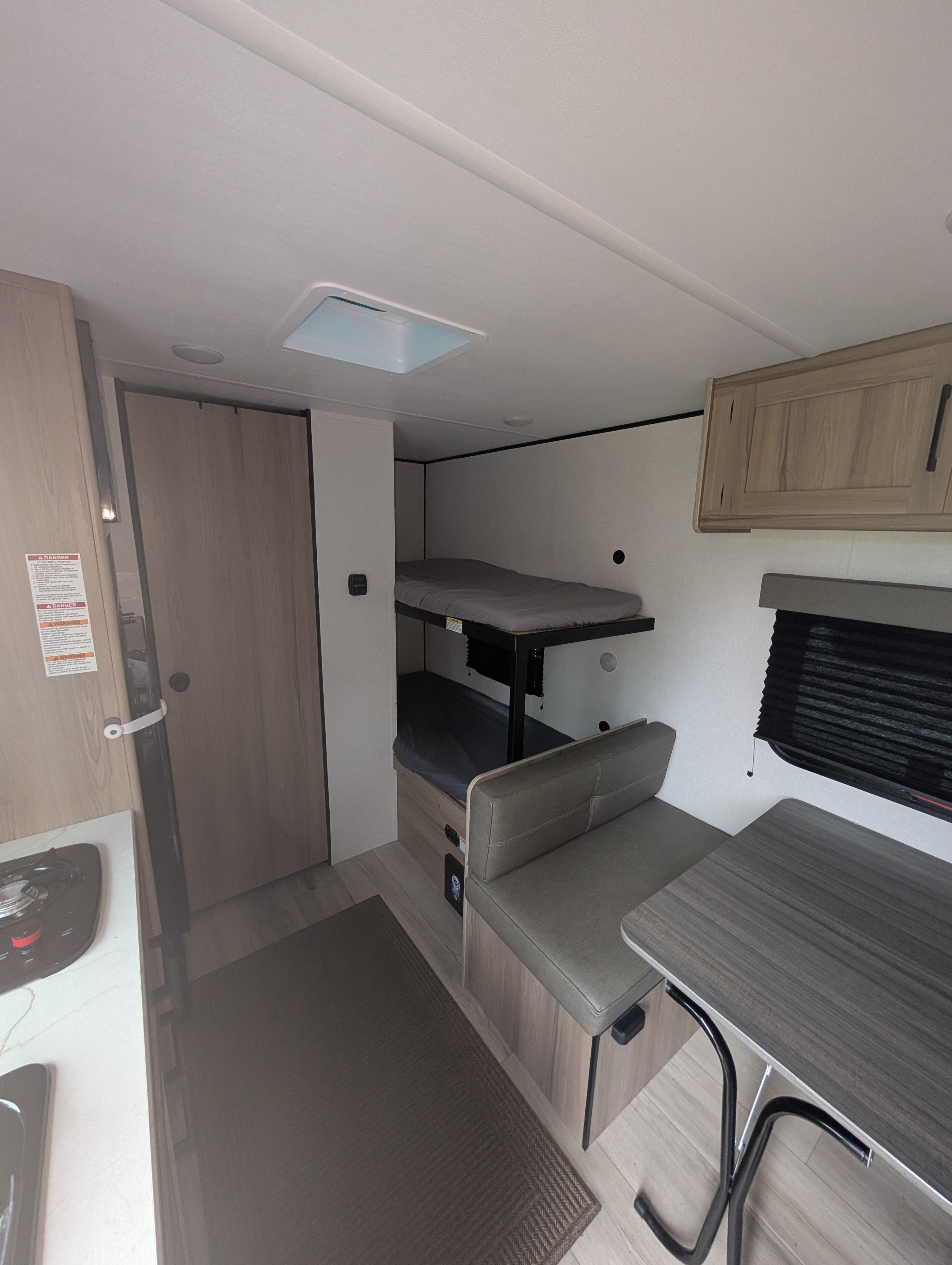RV rental interior features bunk beds, a dinette, and a small kitchen area with a cooktop for compact living.. Coleman 17B 2025