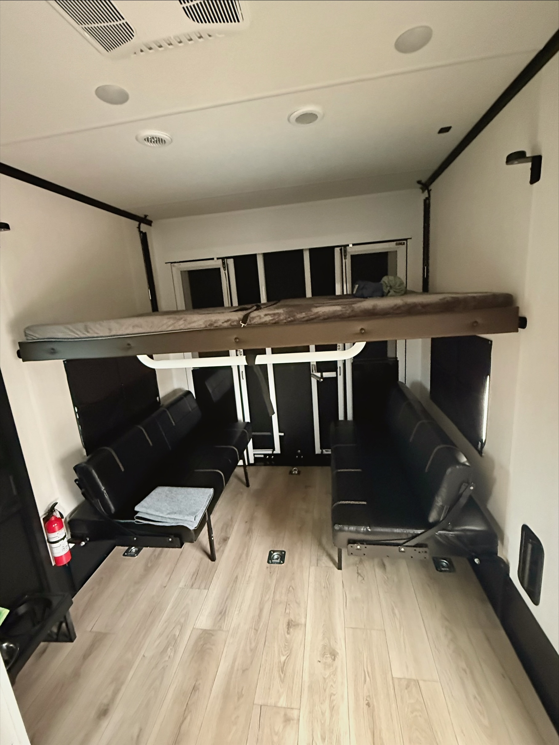 RV rental interior: raised bunk bed, two black convertible sofas, wood floor. Adaptable living & sleeping space.. Forest River Vengeance 2026
