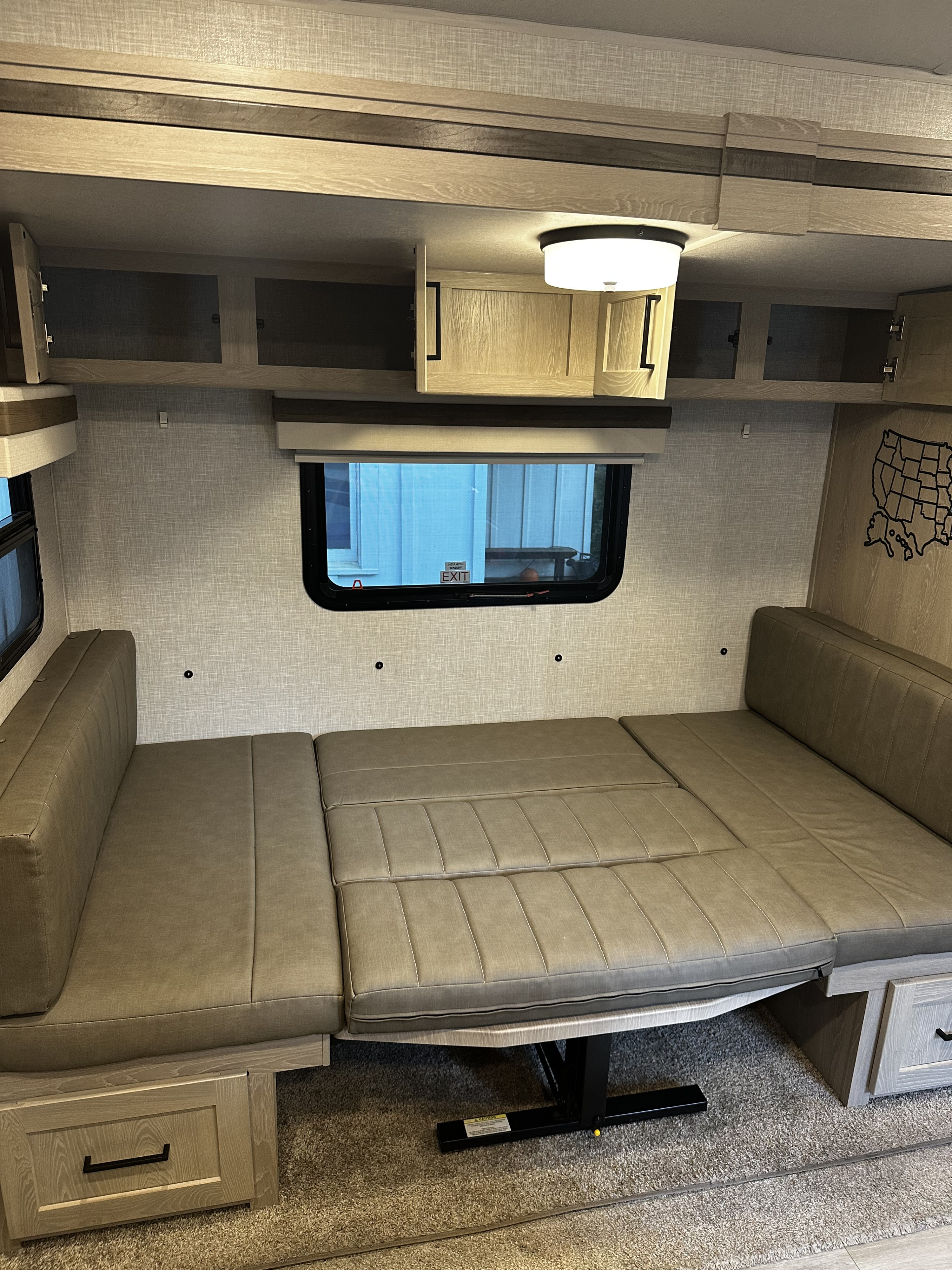 RV rental dinette converts to a bed with overhead storage and window, showcasing a practical interior.. Forest River Rockwood Mini Lite 2022