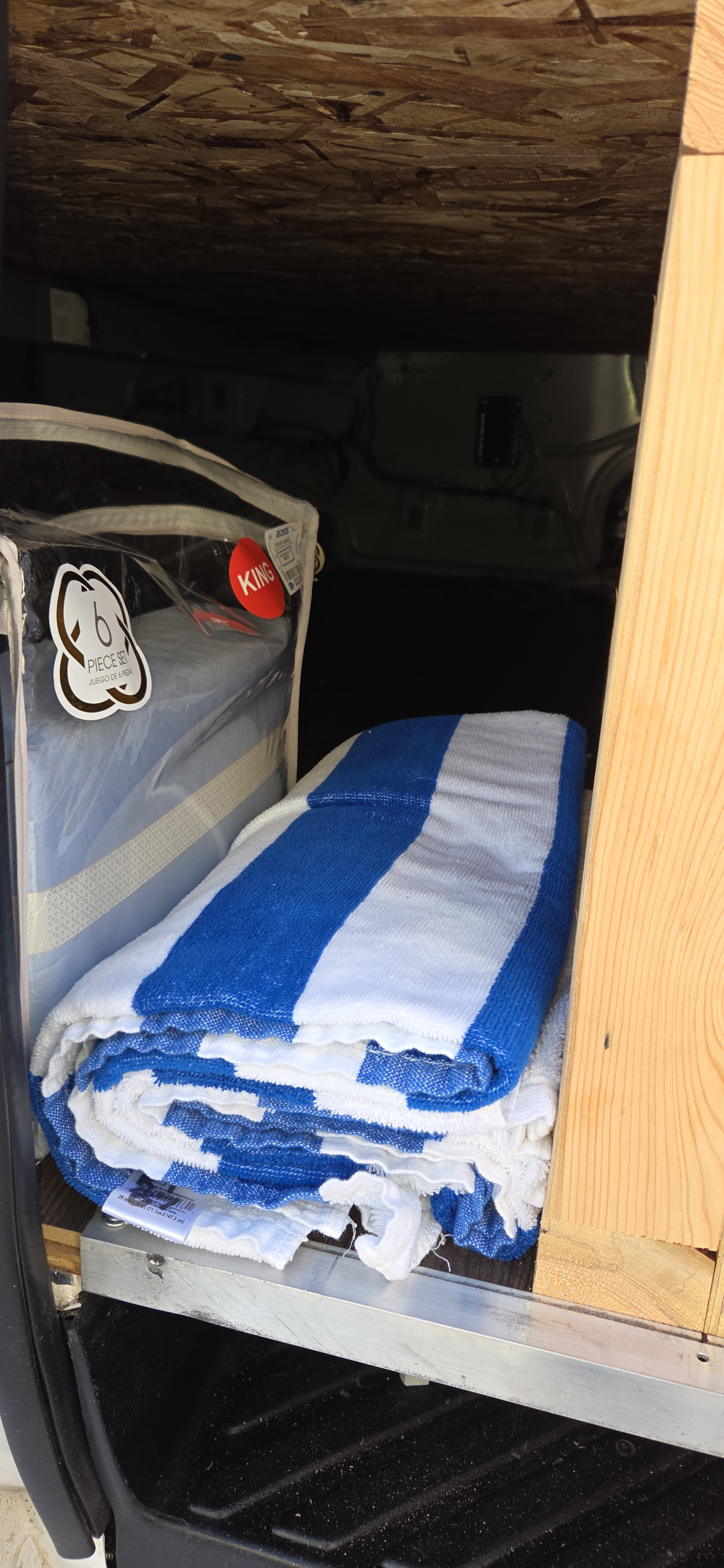 Bedding and blue/white towels neatly stowed in an RV rental's storage space.. Ford Econolline 250s 2005