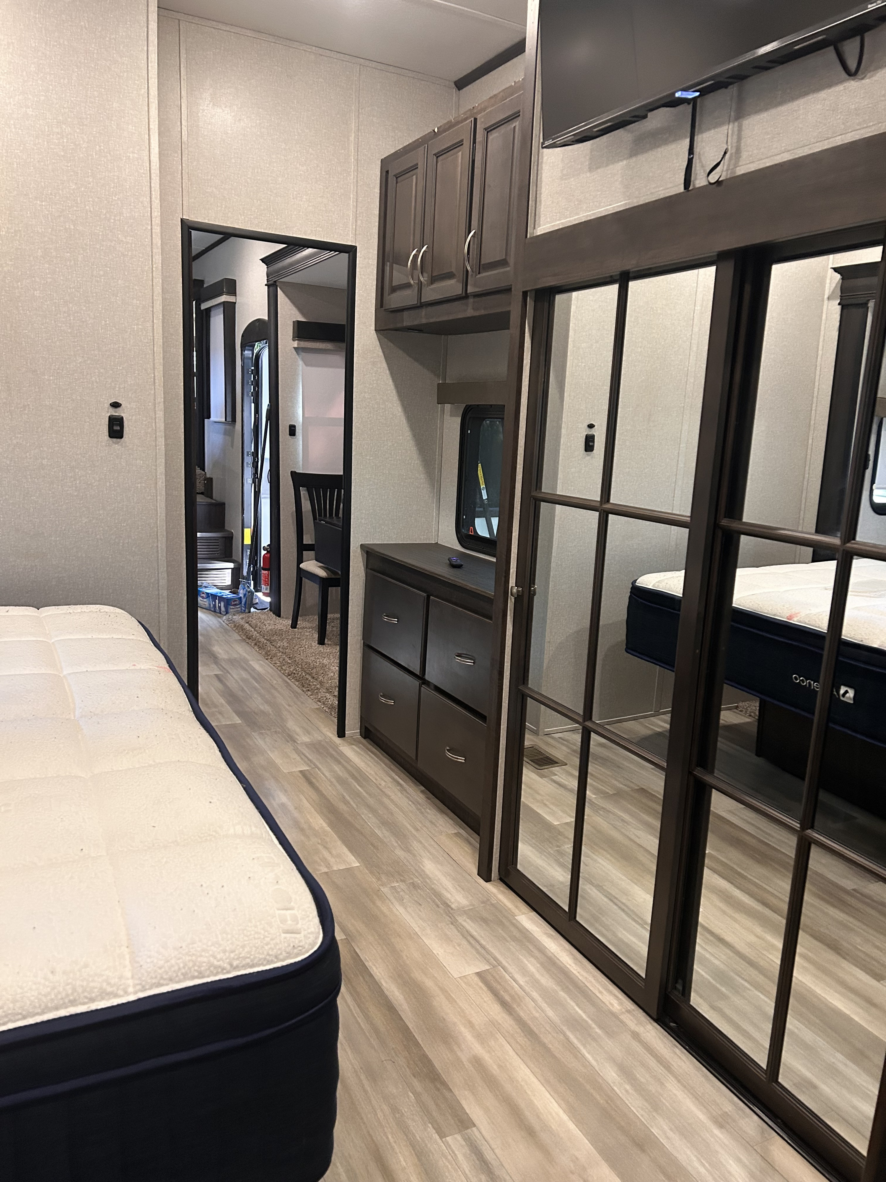 RV rental bedroom: light walls, bed, dark wood dresser, and mirrored closet. Hallway views into the rest of the RV.. Coachmen 2021