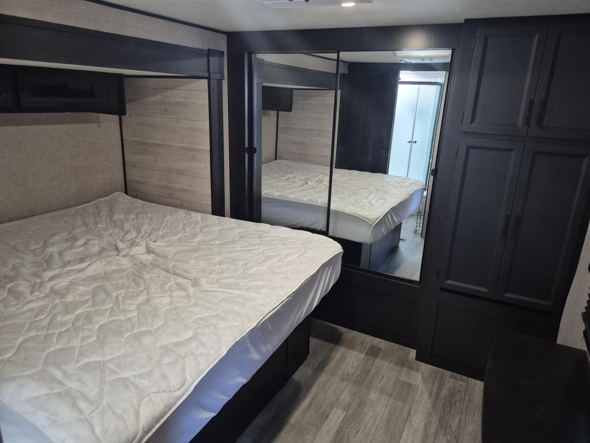 Spacious RV rental bedroom with a comfy bed, modern headboard, overhead storage, and mirrored wardrobe reflecting the interior.. Jayco Jay Flight 2023