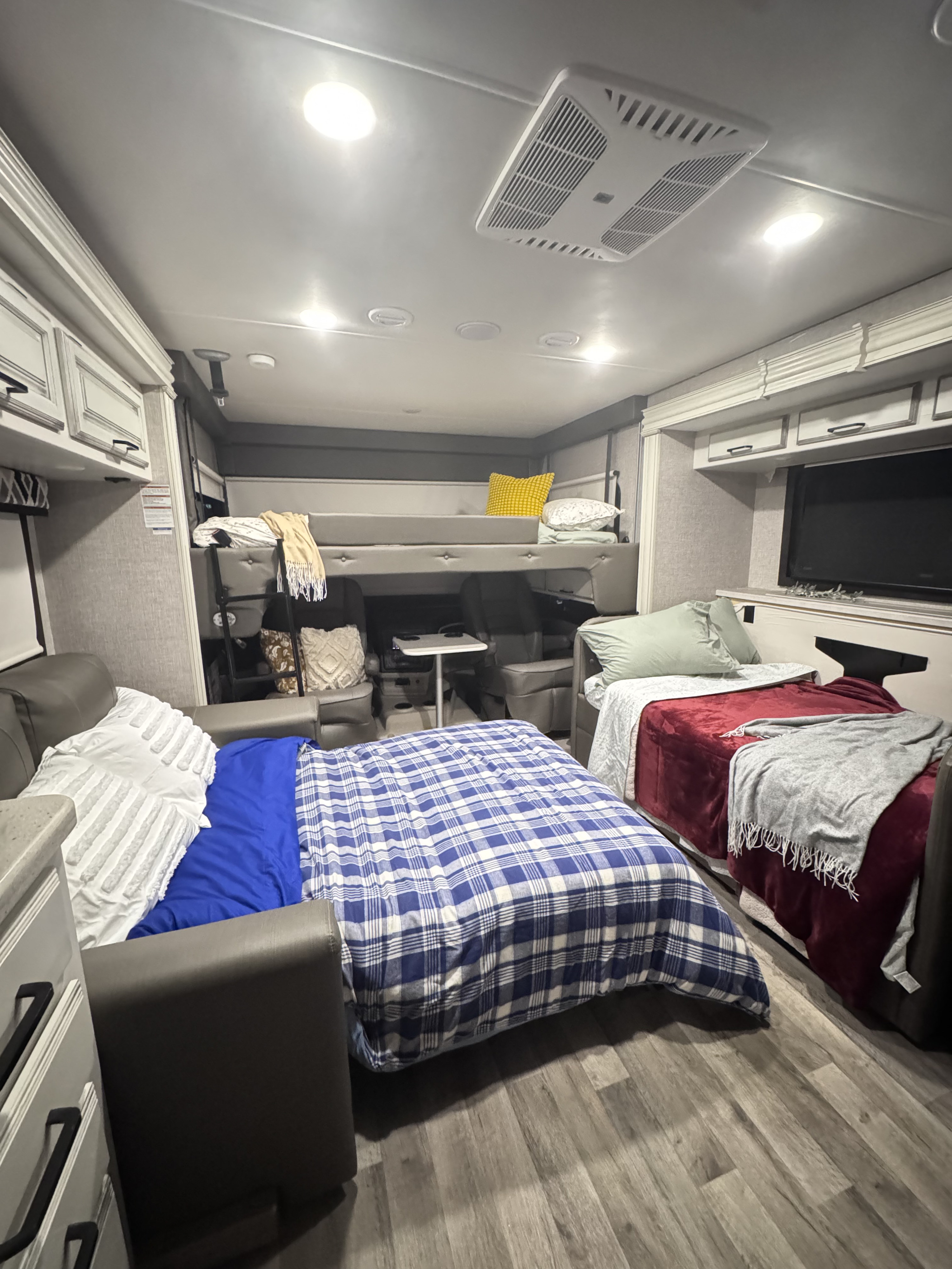 This RV rental interior features a bunk bed, sofa bed, another bed, TV, and bright overhead lighting.. Jayco Precept 2022