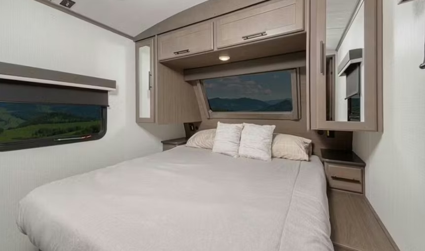 Cozy RV rental bedroom with queen bed, scenic windows, and ample storage. Ideal for comfortable travel adventures.. Keystone RV Cougar 2022