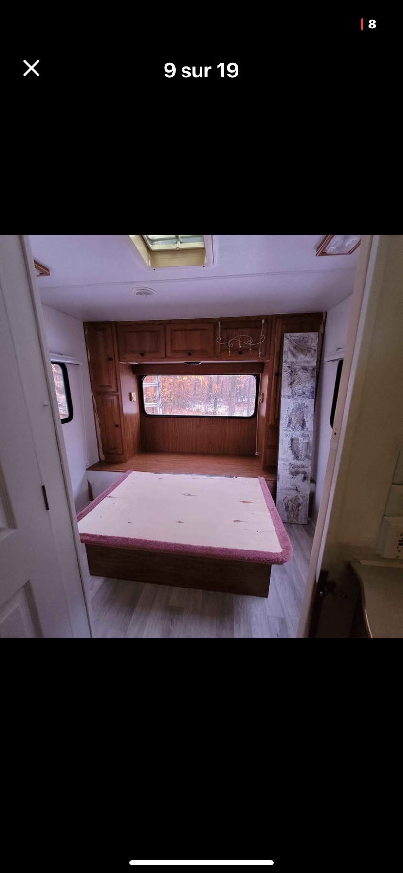 RV rental bedroom interior with wooden bed frame and wood paneling, featuring a large window.. Travel Lite CTV 1999