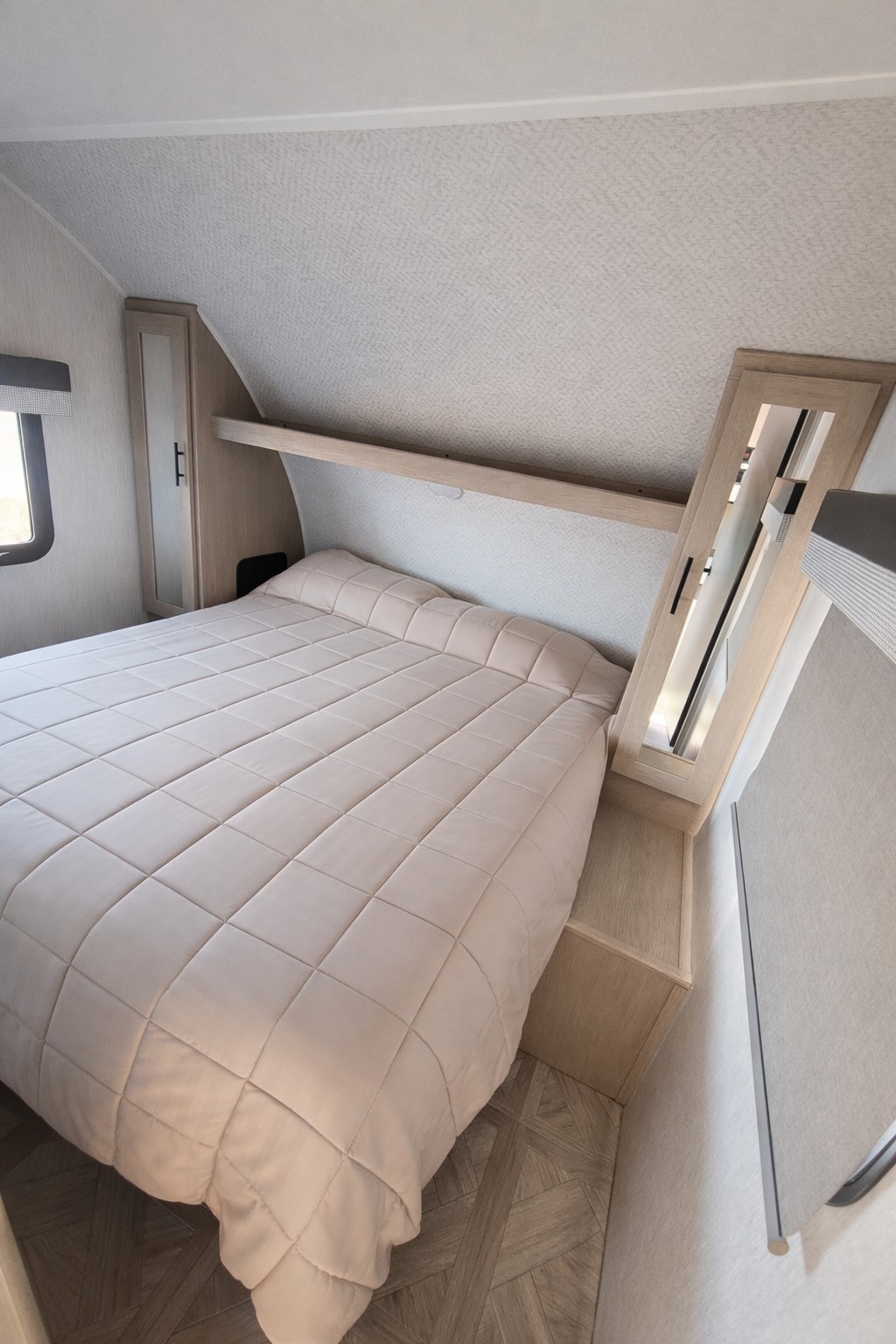 Cozy RV rental bedroom with a comfortable quilted bed, built-in storage, and mirror. Ideal for compact travel.. Forest River Salem Cruise Lite 2023