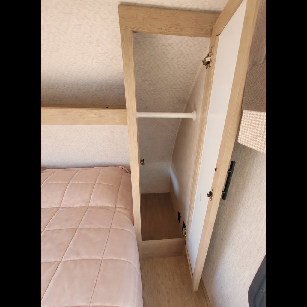 RV rental sleeping area: bed & open wardrobe with hanging bar. Functional storage for travel clothes.. Forest River Salem Cruise Lite 2023