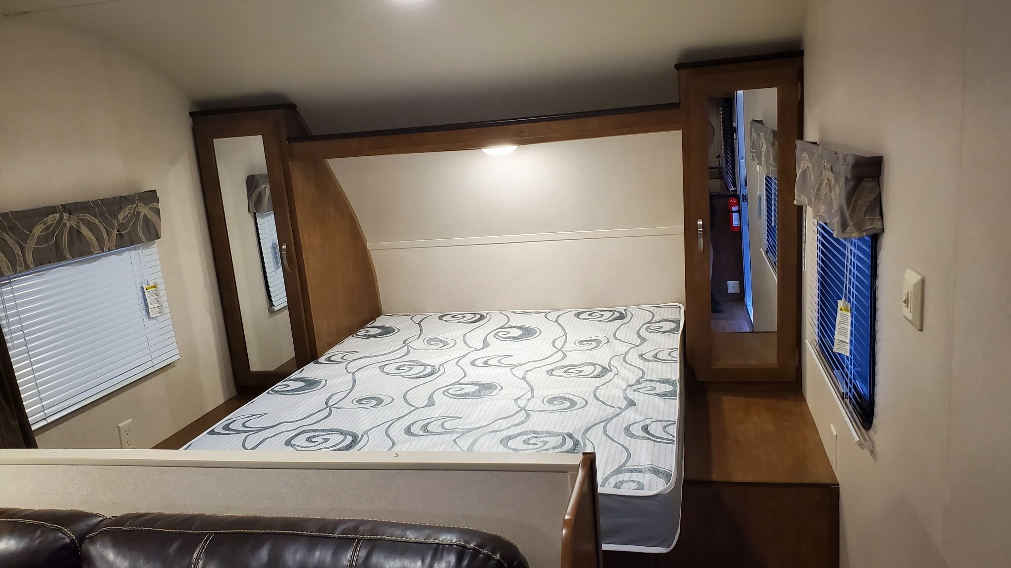 This RV rental bedroom features a comfy bed, built-in storage, window blinds, and overhead lighting for your travels.. Forest River Wildwood X-Lite 2018