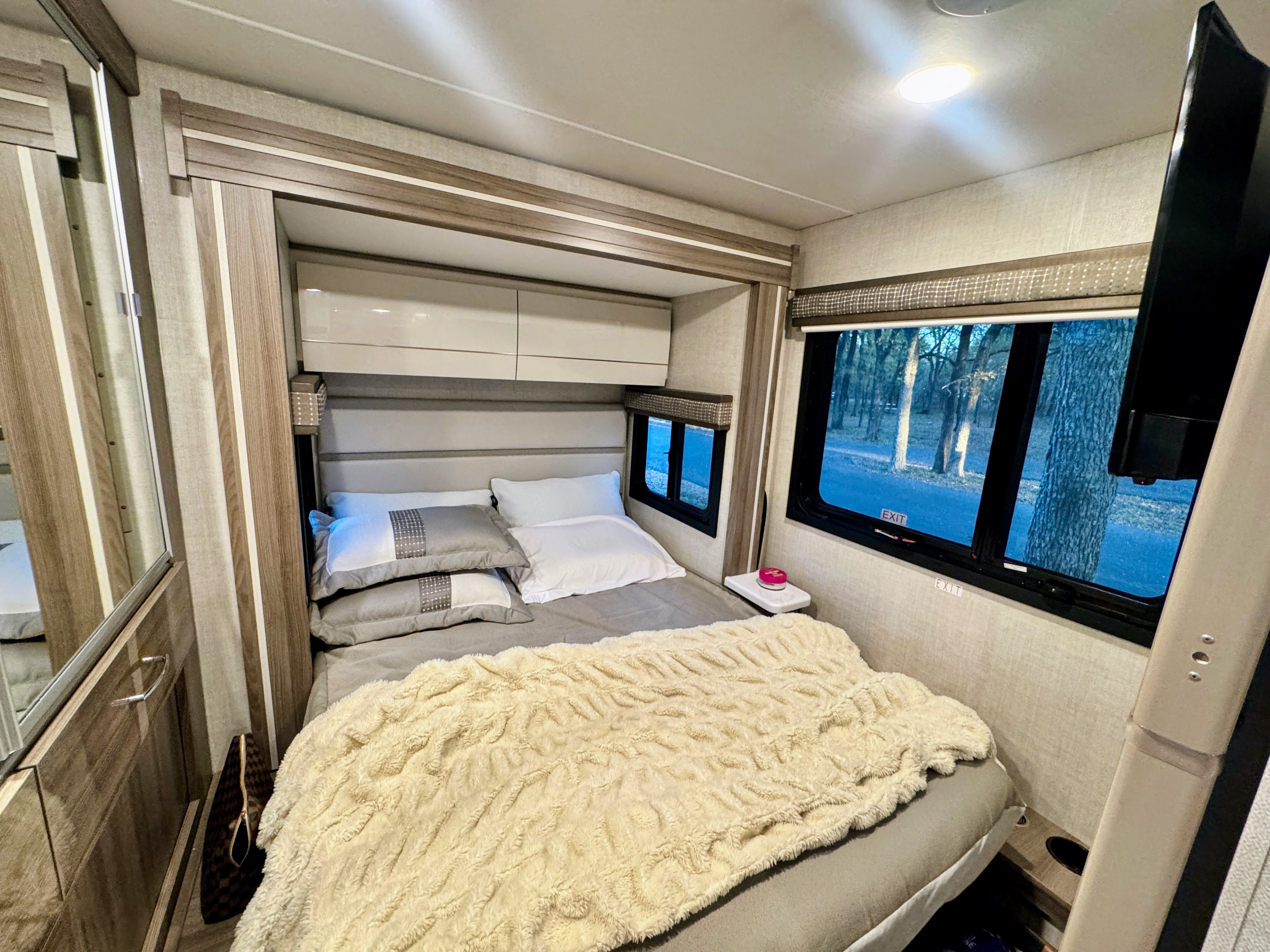 Cozy RV rental bedroom with a comfy bed, overhead storage, and scenic window views, perfect for travel.. Mercedes Sprinter Thor Tiburon 2026