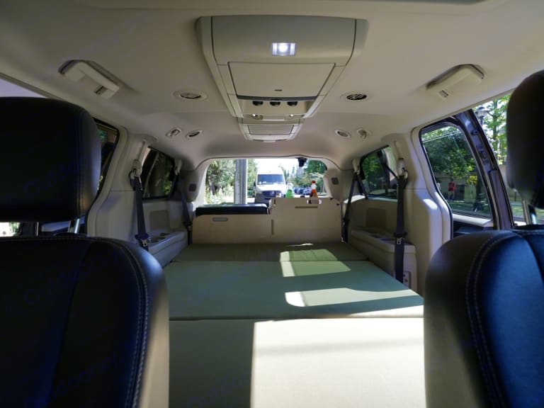 Inside an RV rental, a minivan converted with a sleeping platform, ready for camping adventures or van life travel.. Chrysler Town & Country 2012