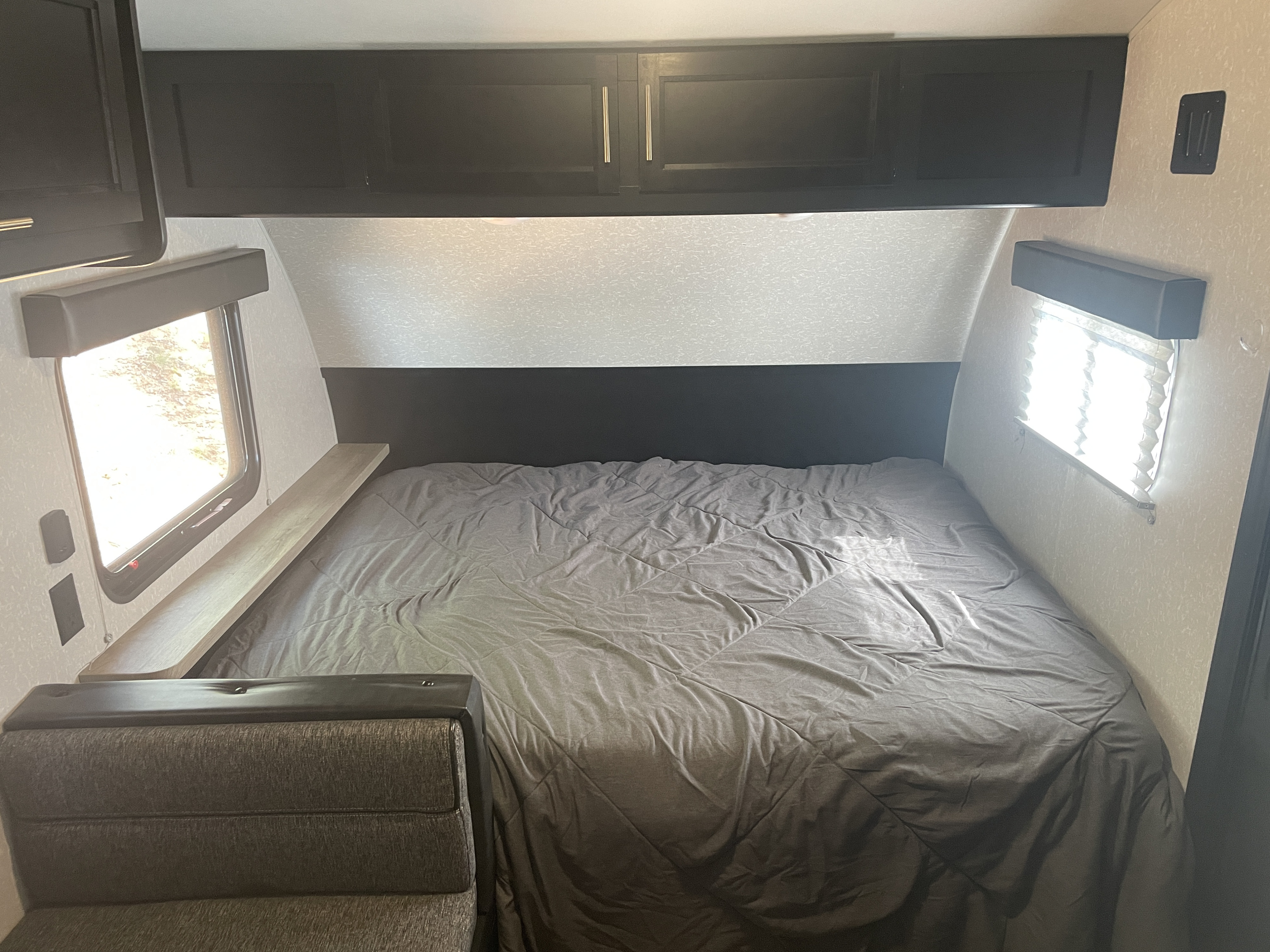 Cozy RV rental bedroom with dark cabinets, a comfy bed, and windows for natural light. Ideal for a relaxing trip.. Forest River Cherokee Wolf Pup 2022