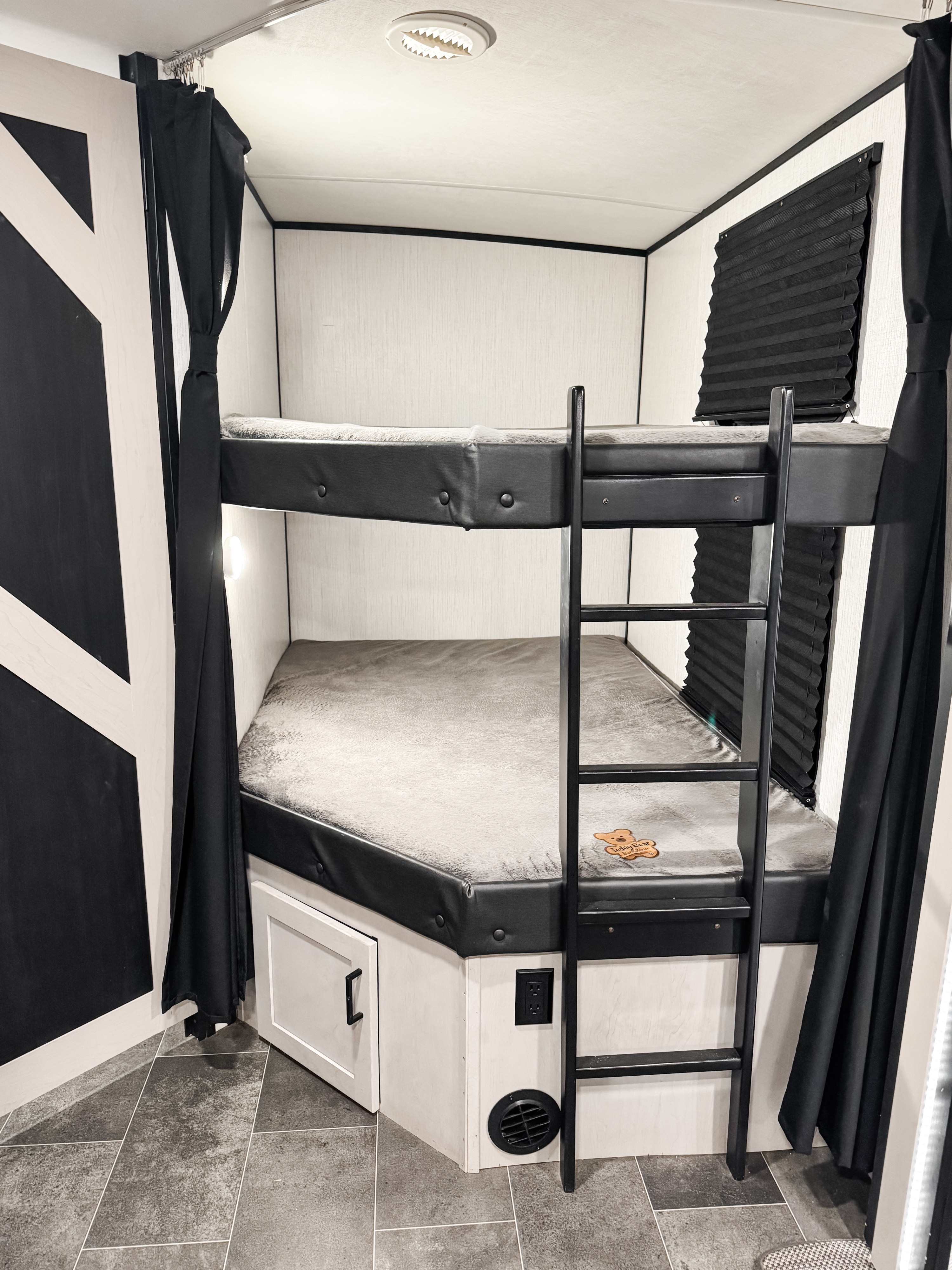 RV rental bunk room showing two beds with black ladder, privacy curtains, cabinet, and floor vent.. Heartland Mallard M312 2022