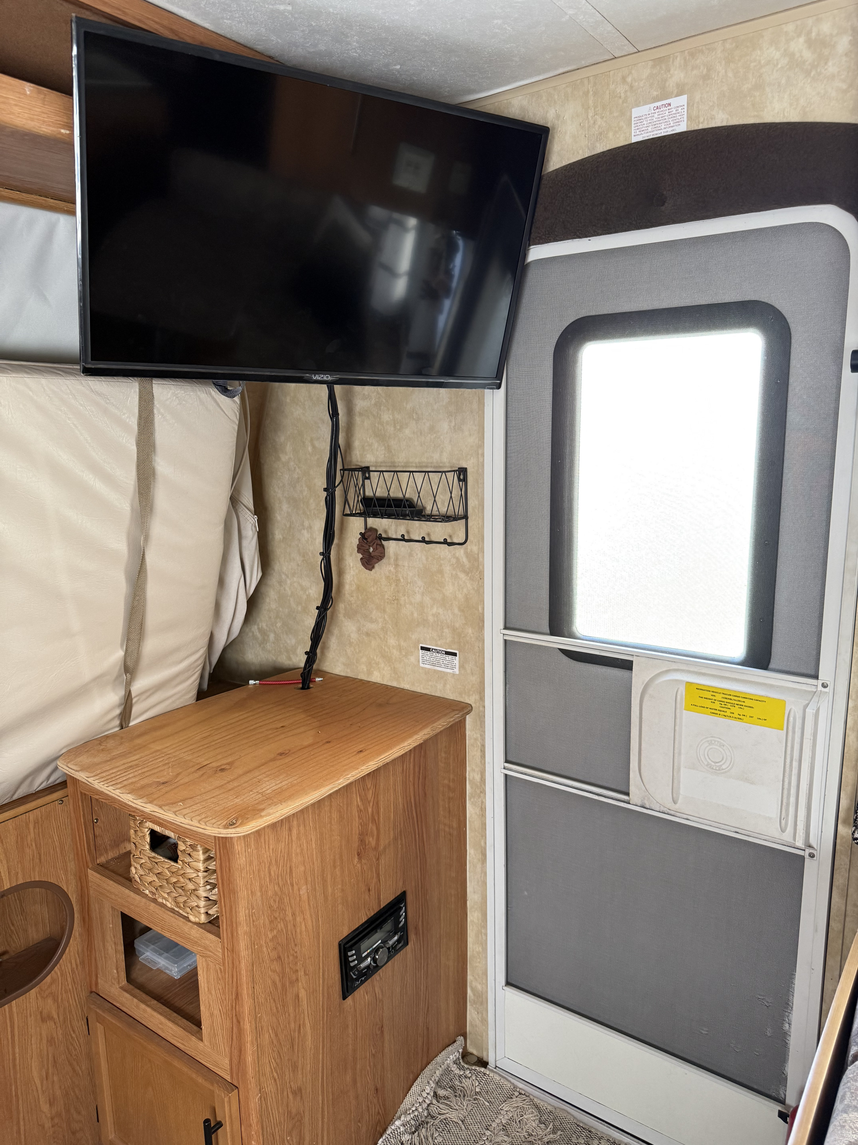 **rv rental** interior featuring a mounted TV, wooden cabinet with radio, and screen door, ideal for compact living.. Jayco Jay Feather EXP 2010