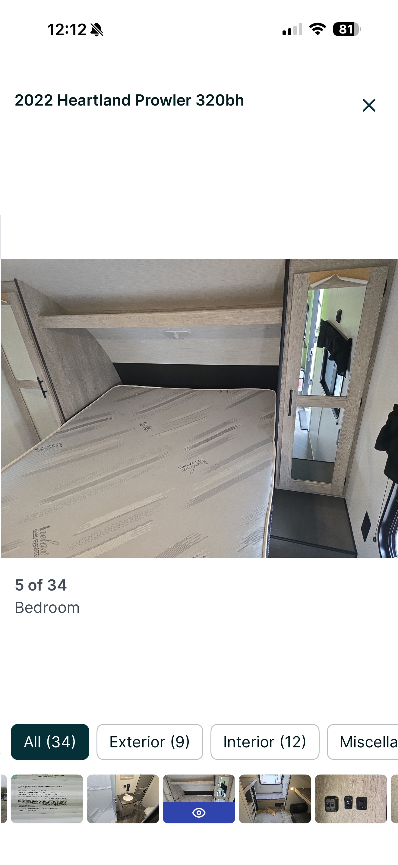 Inside a 2022 Heartland Prowler 320bh rv rental: a light-colored bed, overhead shelf, and mirrored cabinet in the bedroom.. Heartland RVs Prowler 2022