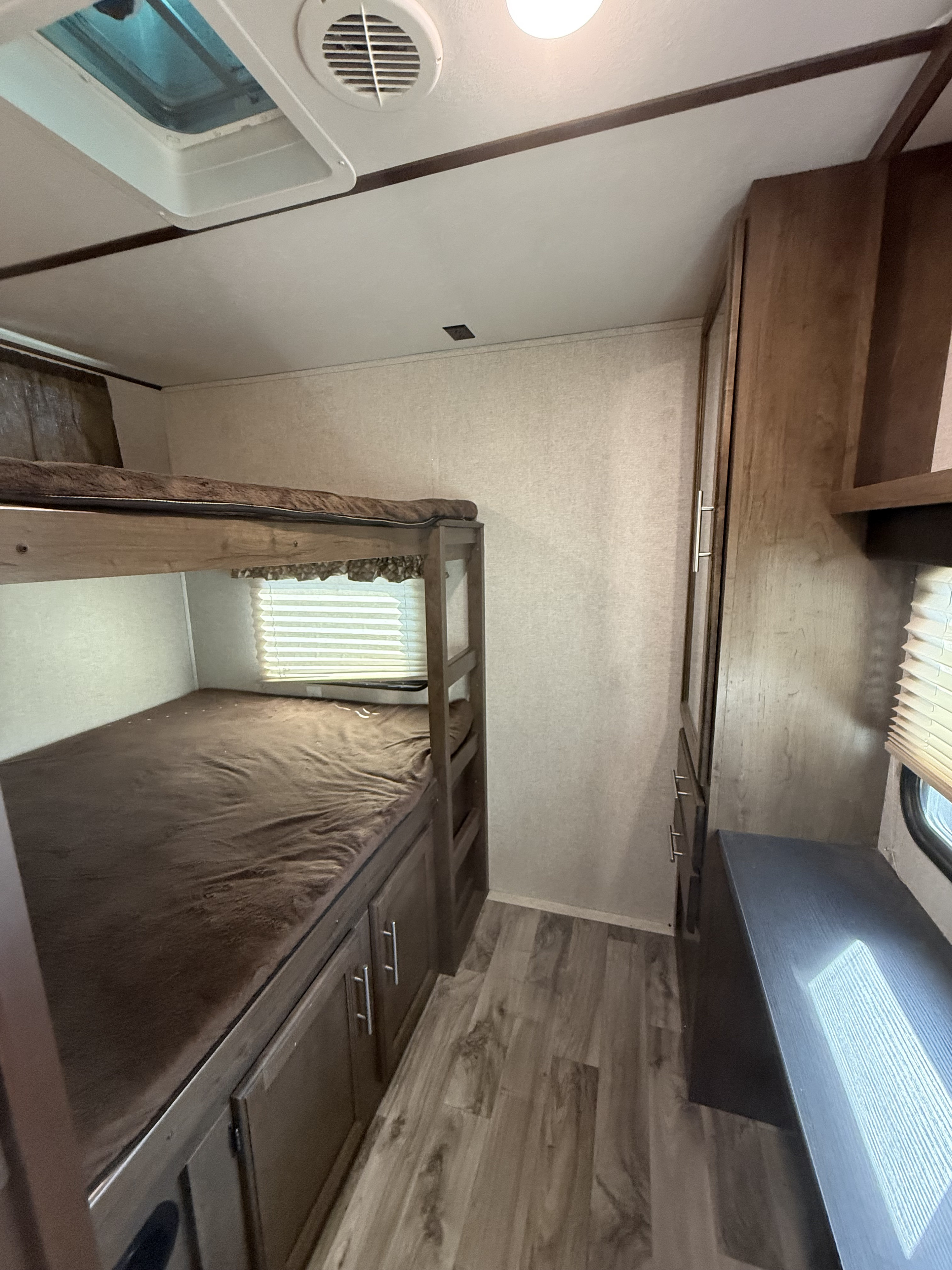 RV rental bunkhouse area: brown bunk beds, built-in storage, and wardrobe. Compact and functional RV sleeping space.. Keystone RV Cougar 2018