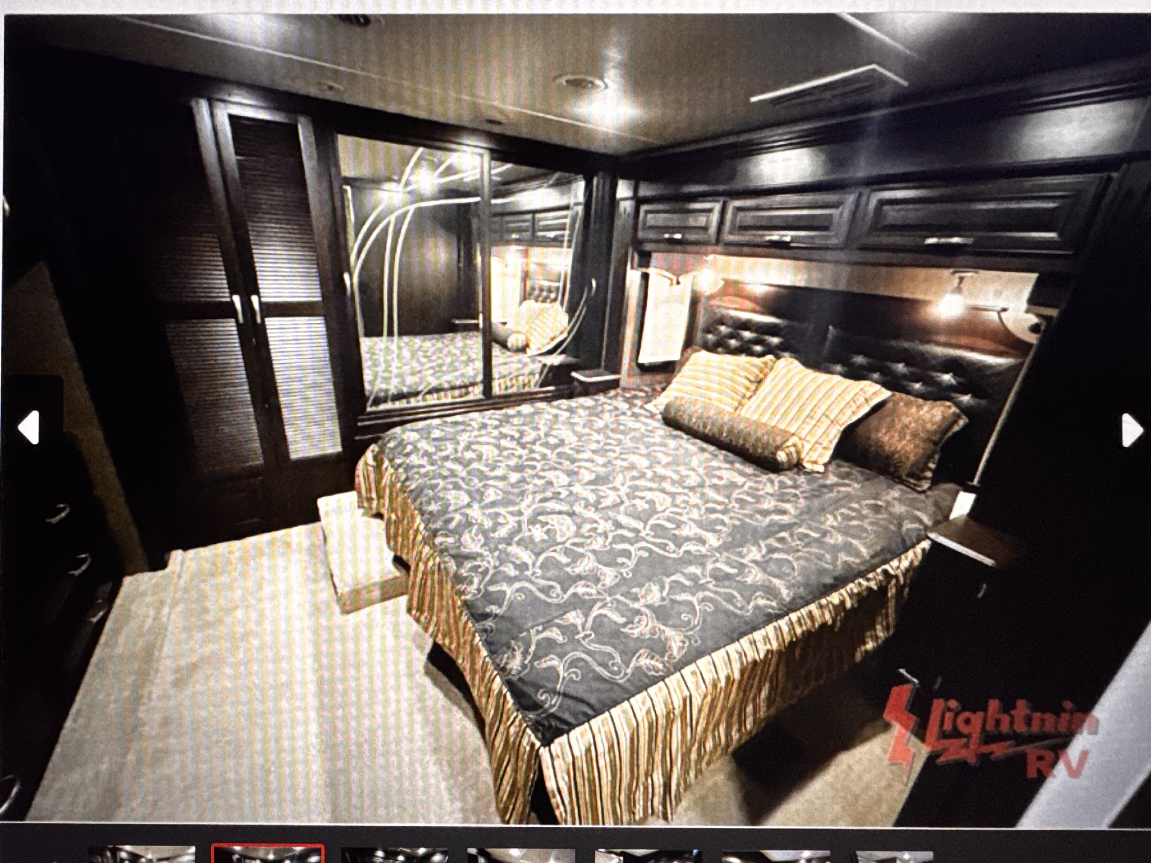 Spacious RV rental bedroom with a large bed, dark wood cabinetry, mirrored closet doors, and overhead storage.. Berkshire XLT 2016