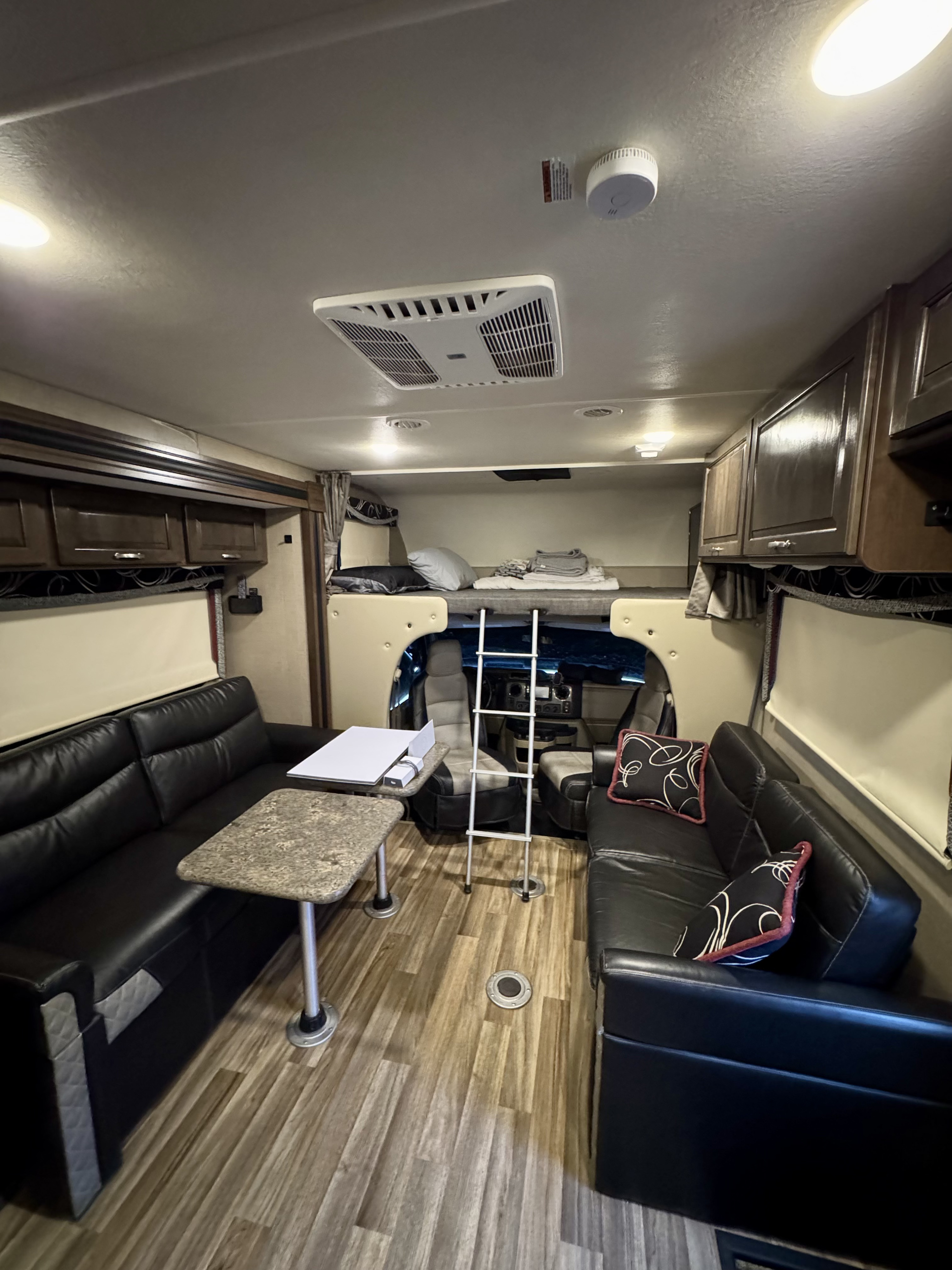 Spacious RV rental interior with comfortable sofas, dining area, and over-cab bunk bed for a cozy trip.. Thor Outlaw 2019