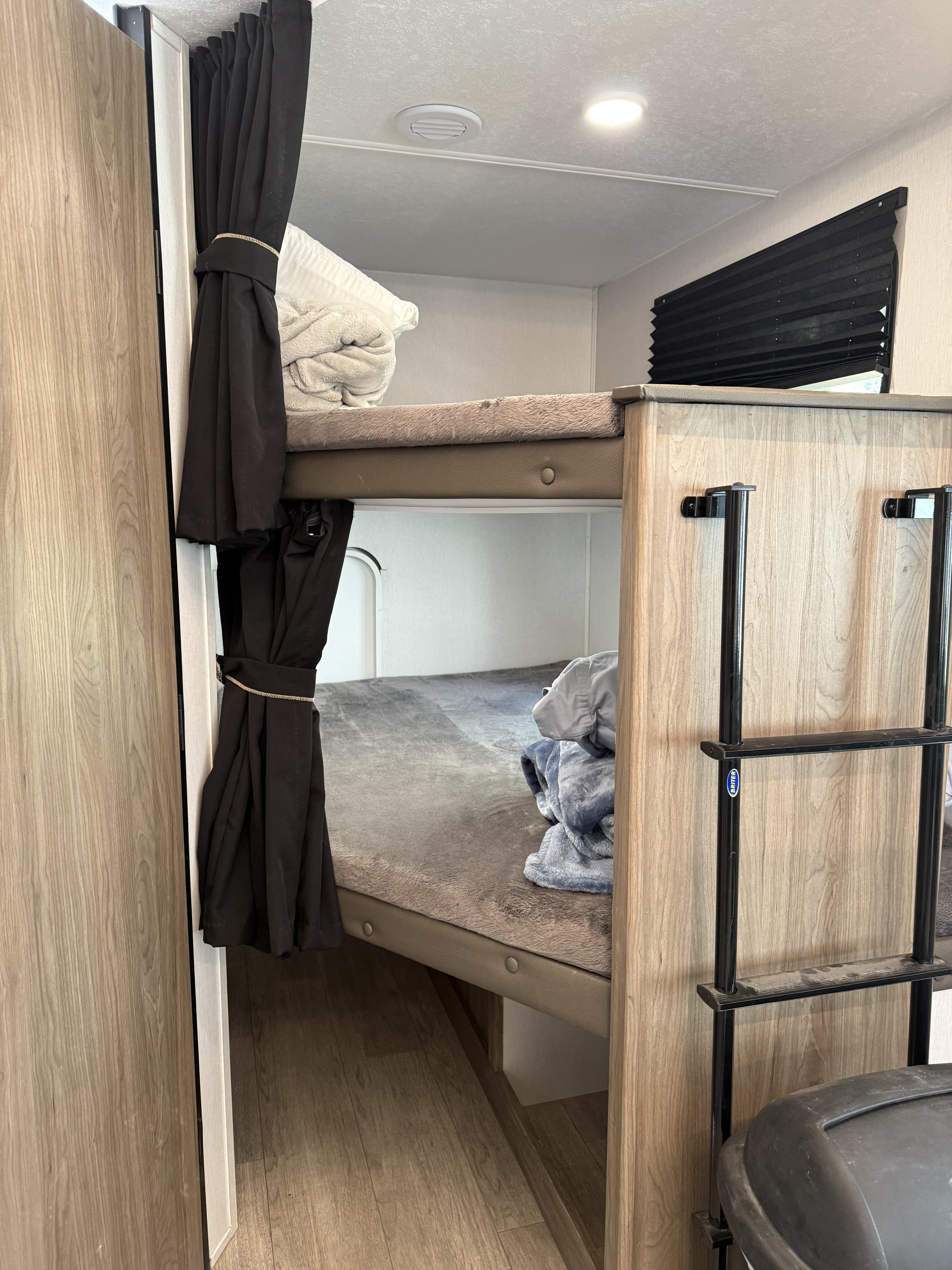 Cozy RV rental bunk beds, complete with privacy curtains, a ladder, and comfortable bedding.. Forest River Coachmen Freedom Express 2025