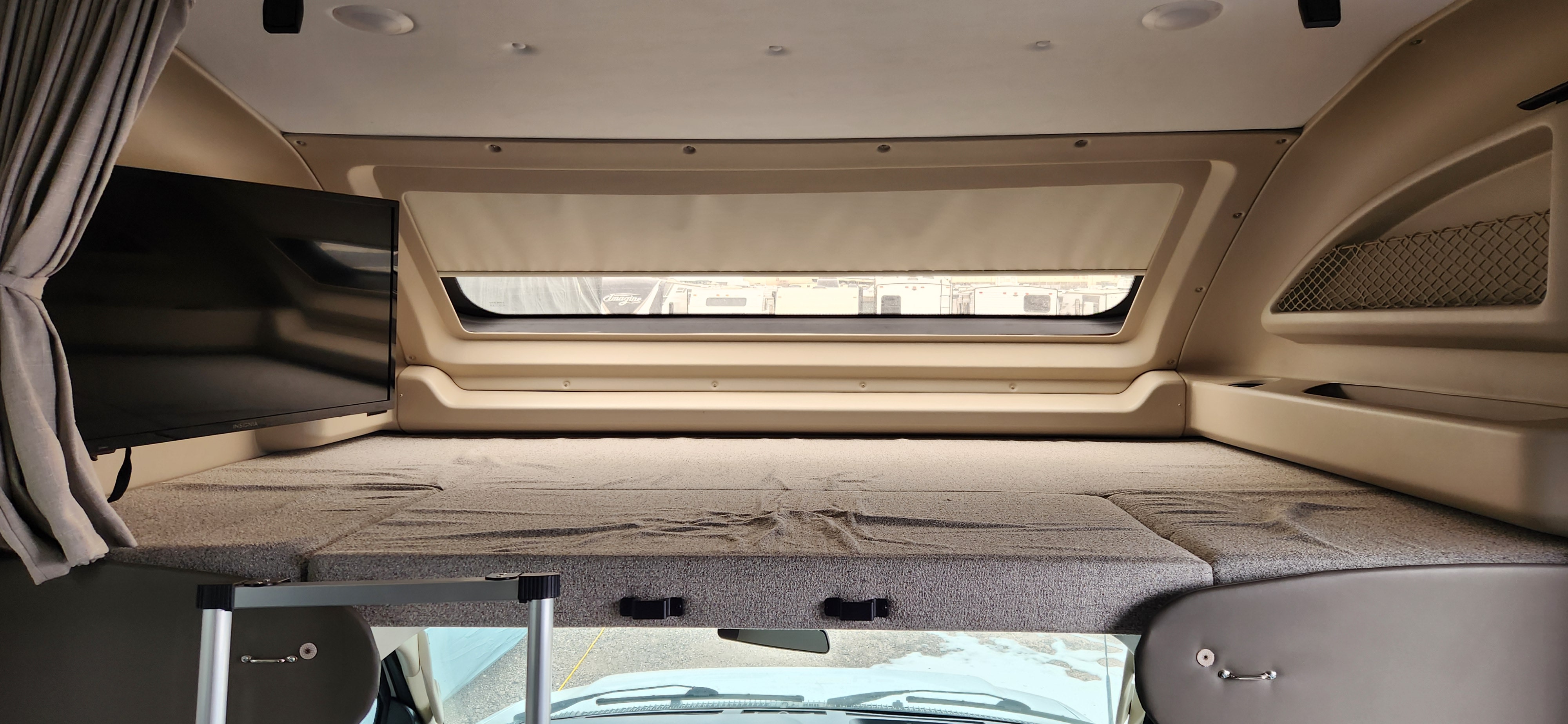 **RV rental** over-cab bunk bed with TV, window view & storage net. A cozy **sleeping area** for your adventure.. Jayco Greyhawk 2024