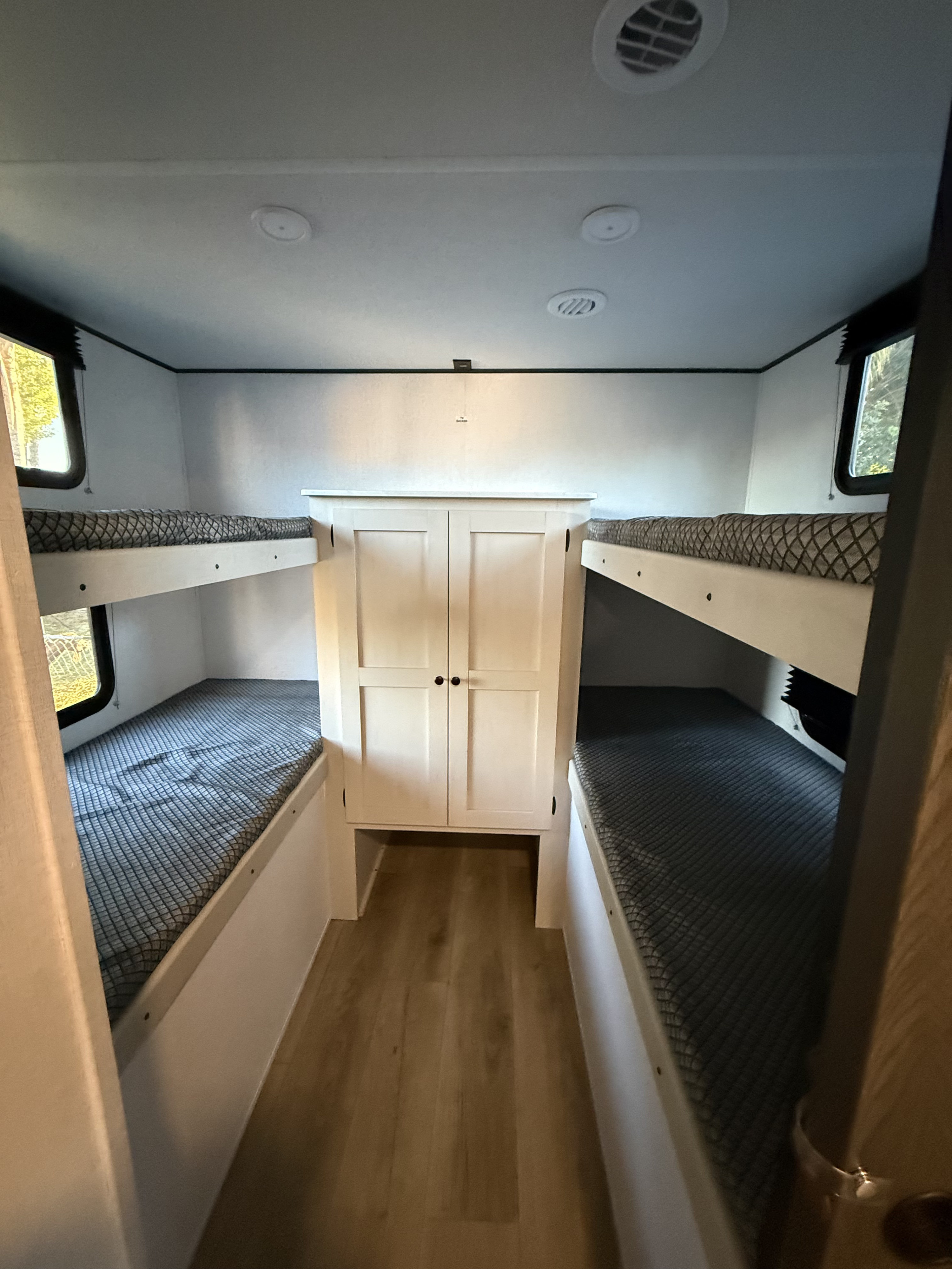 This RV rental features a cozy bunk bed area with two sets of bunks and a central wardrobe, perfect for family sleeping.. Coachmen Spirit 29BH 2026