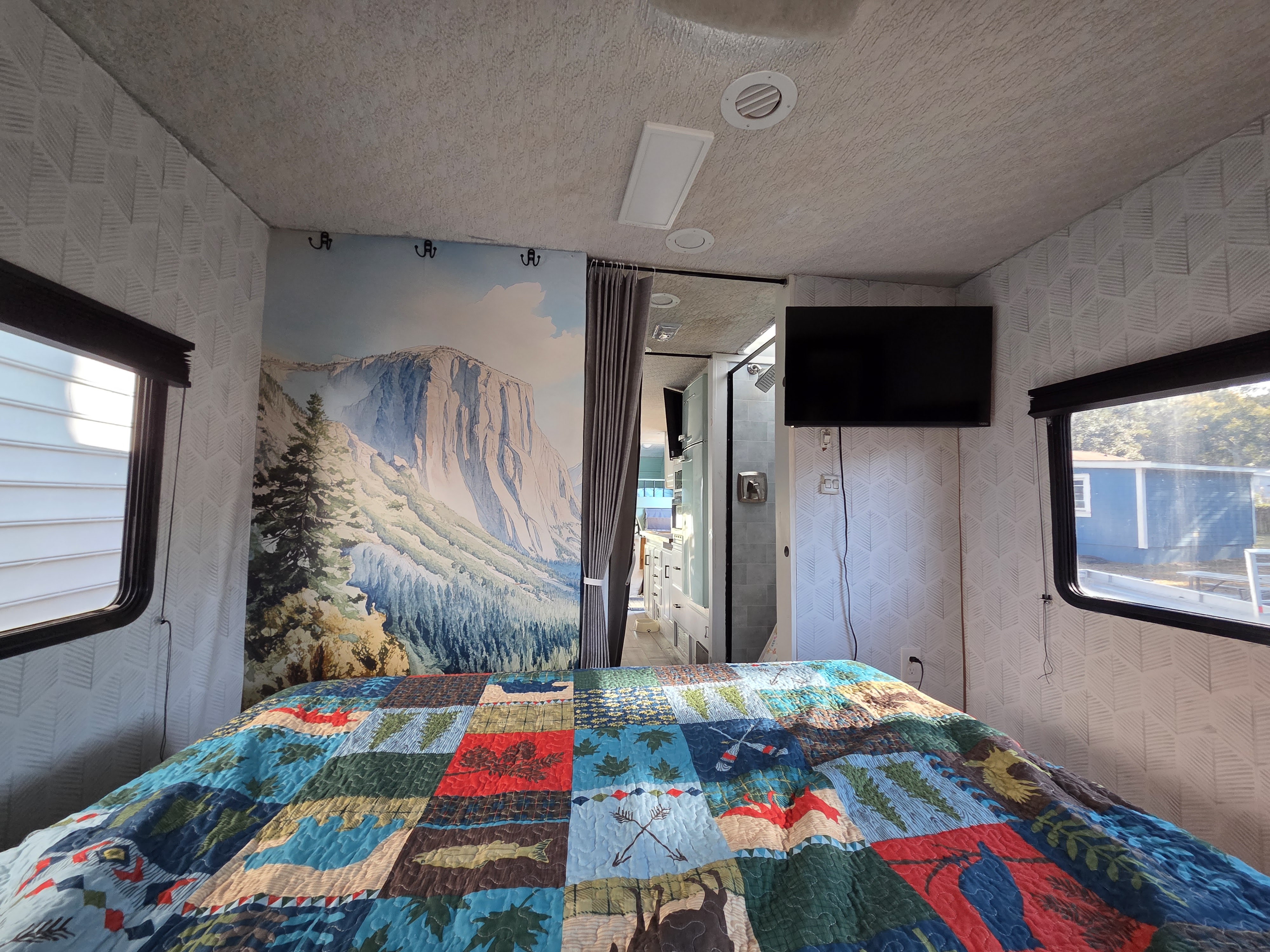 RV rental bedroom with vibrant quilt, mountain mural, and modern decor. Ready for your adventure on the road!. Winnebago Minnie Winnie 2002