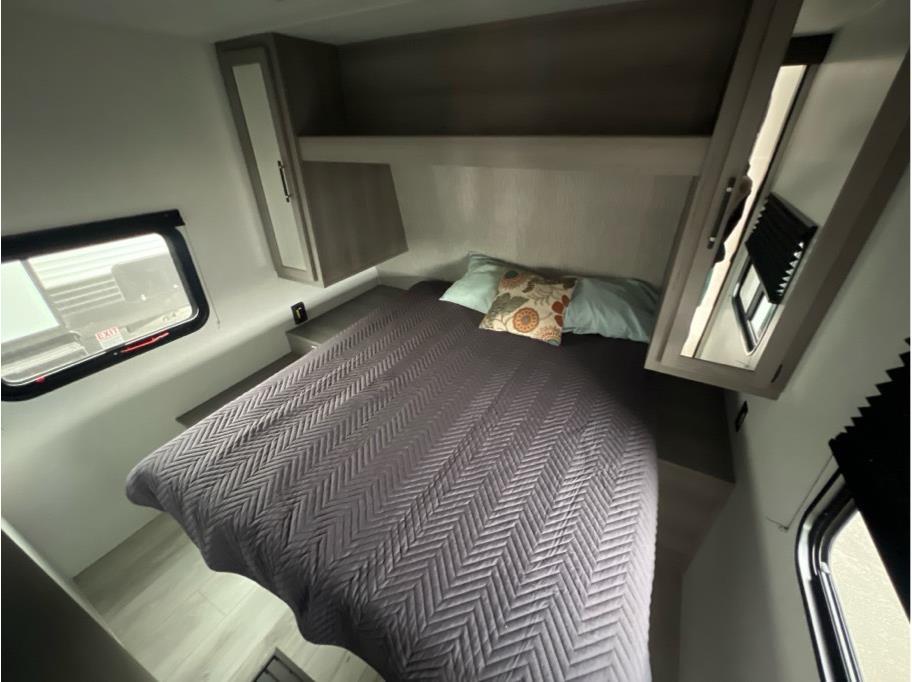 Clean, modern RV rental bedroom with a comfy bed, overhead cabinets, and windows. Perfect for your next adventure.. Keystone RV Hideout Sport 2025