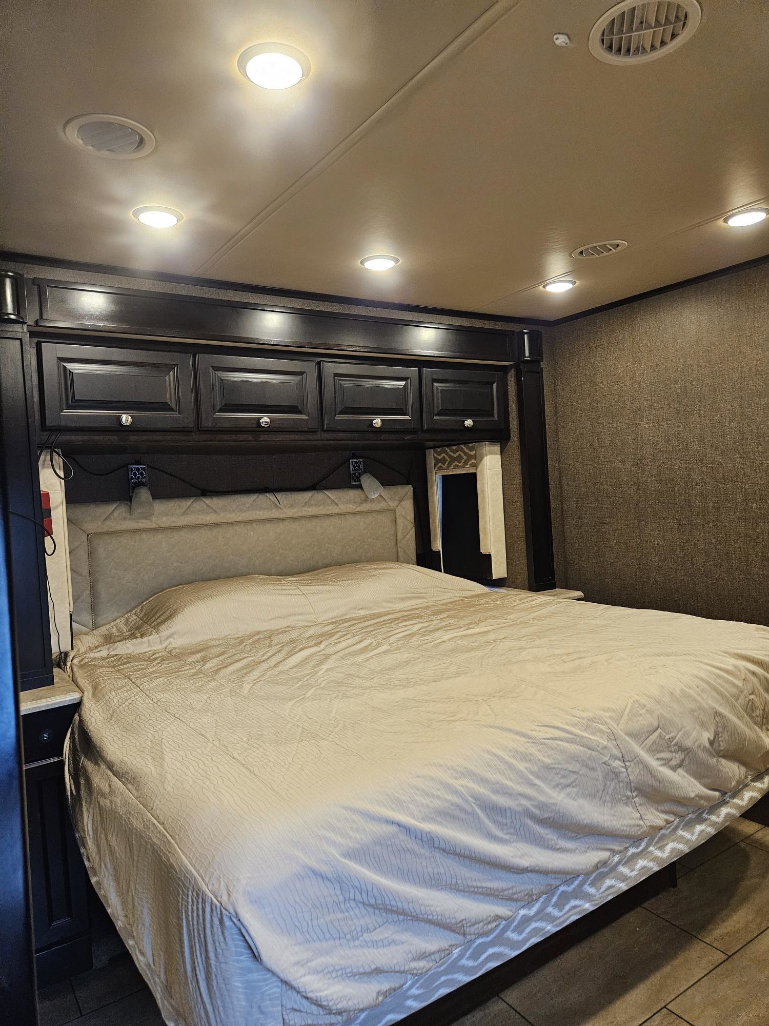 Cozy RV rental bedroom featuring a queen bed, built-in storage, and reading lamps, offering comfort on the road.. Allegro Allegro Open Road 2017