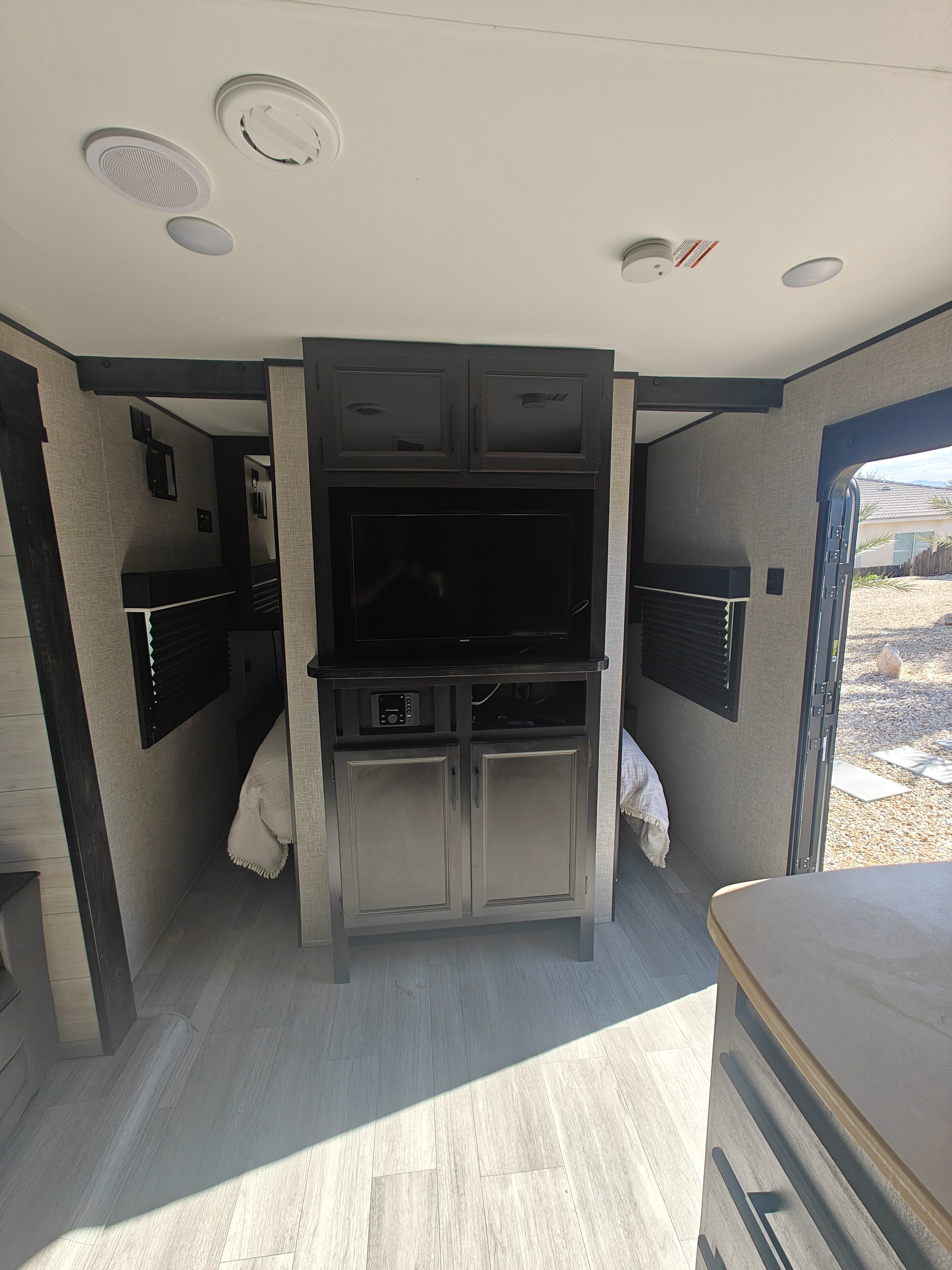 Spacious RV rental interior: central TV and entertainment unit flanked by cozy bunk beds, with light-toned flooring.. Jayco Jay Flight SLX Rocky Mountain Edition 2022