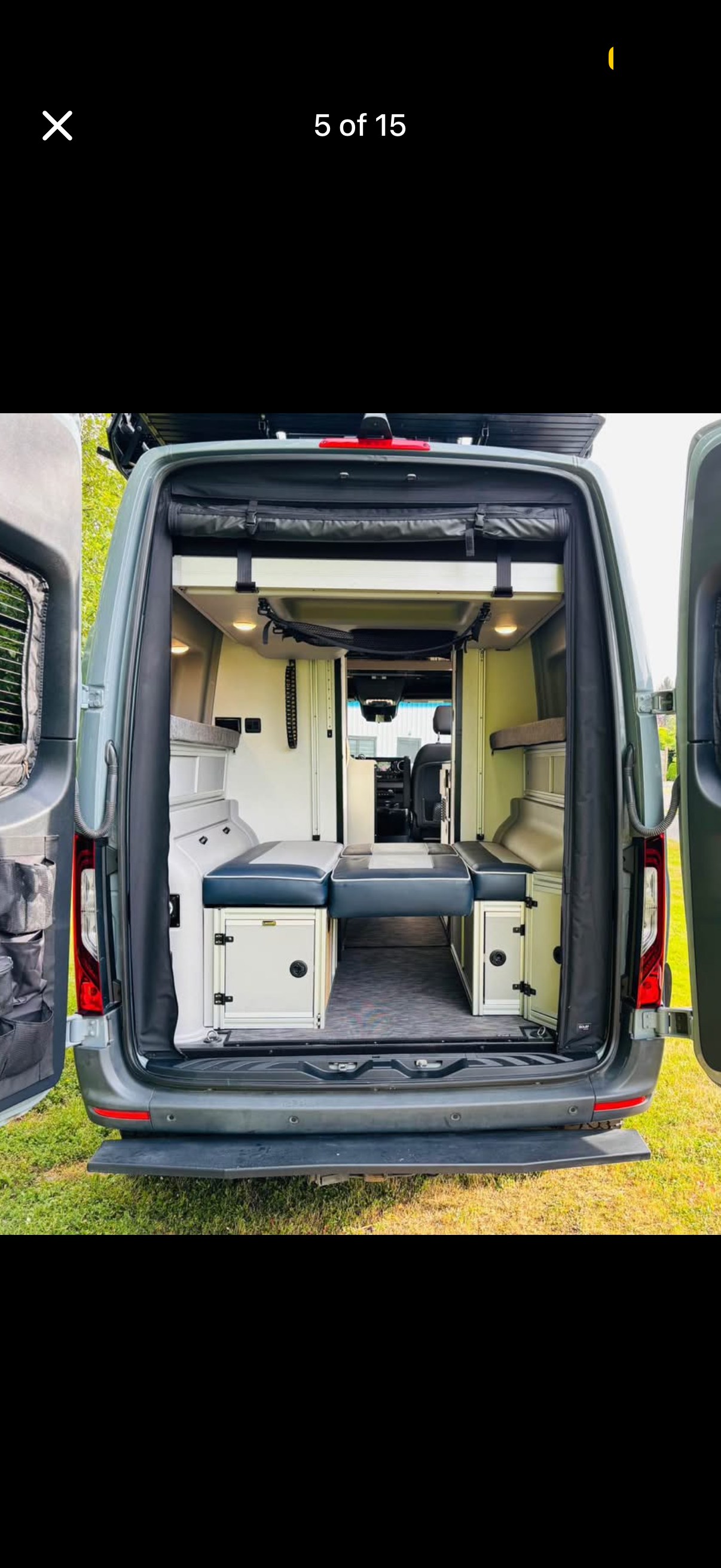 This rv rental shows a custom camper van interior from the rear, featuring modular seating, storage units, and a convertible bed.. Winnebago Revel 2022